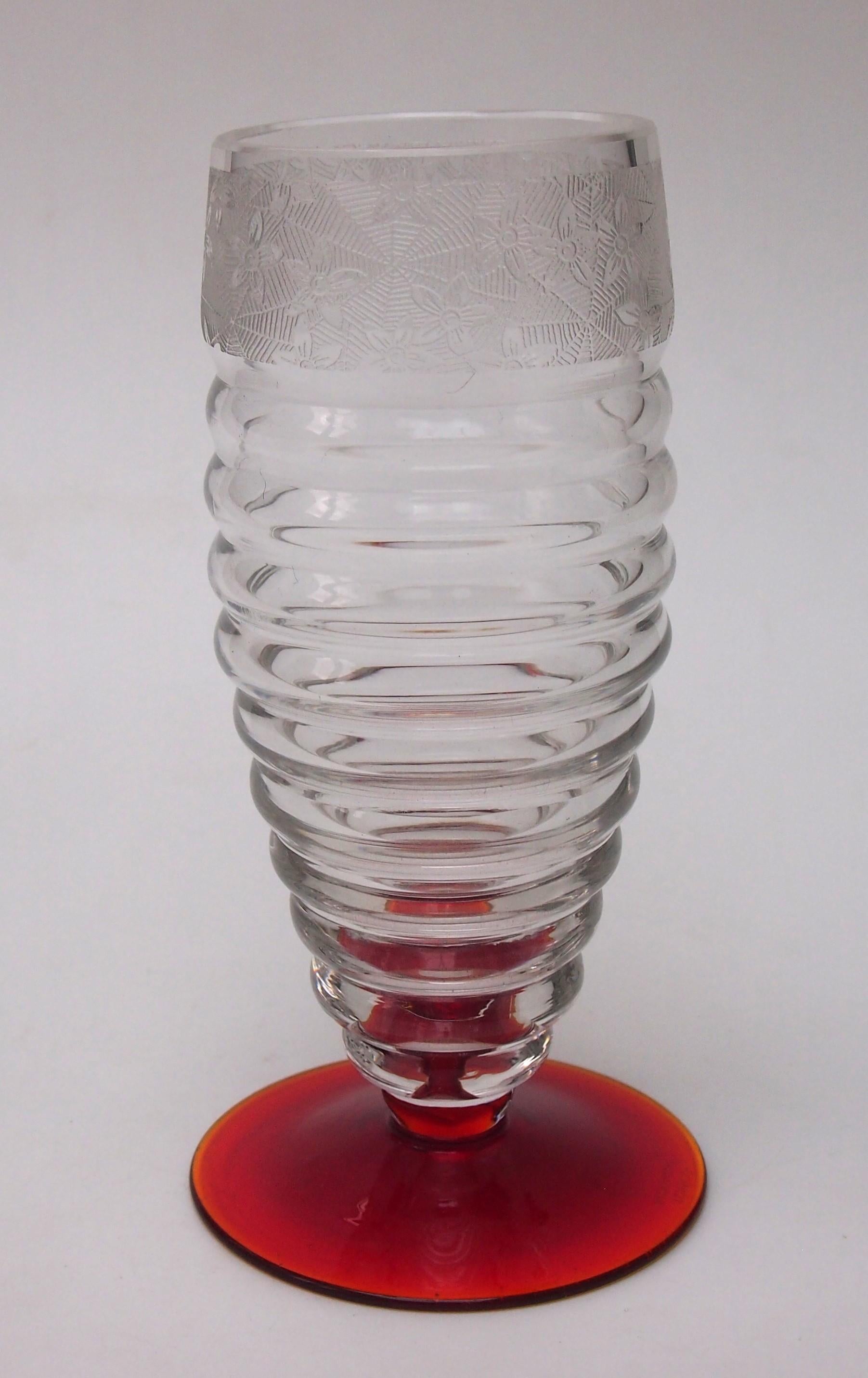 Fabuloso jarrón con pie rojo y bandas transparentes, con un friso de telarañas y flores de fino detalle. Es una obra típica de la región Haida de Checoslovaquia, posiblemente de Carl Metzler o Carl Hosch. El jarrón lleva la marca 