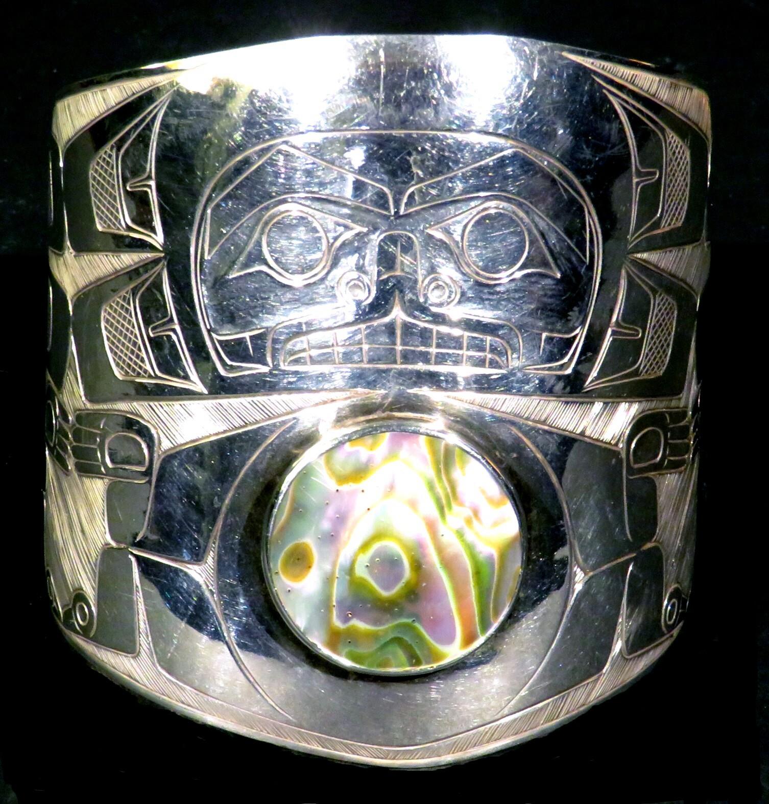 Un impressionnant bracelet-bracelet Haida en argent sterling fabriqué à la main, décoré de motifs totémiques Haida traditionnels et centré par une étonnante rondelle d'ormeau. L'intérieur porte la signature de l'artiste et la date de 1979, ainsi