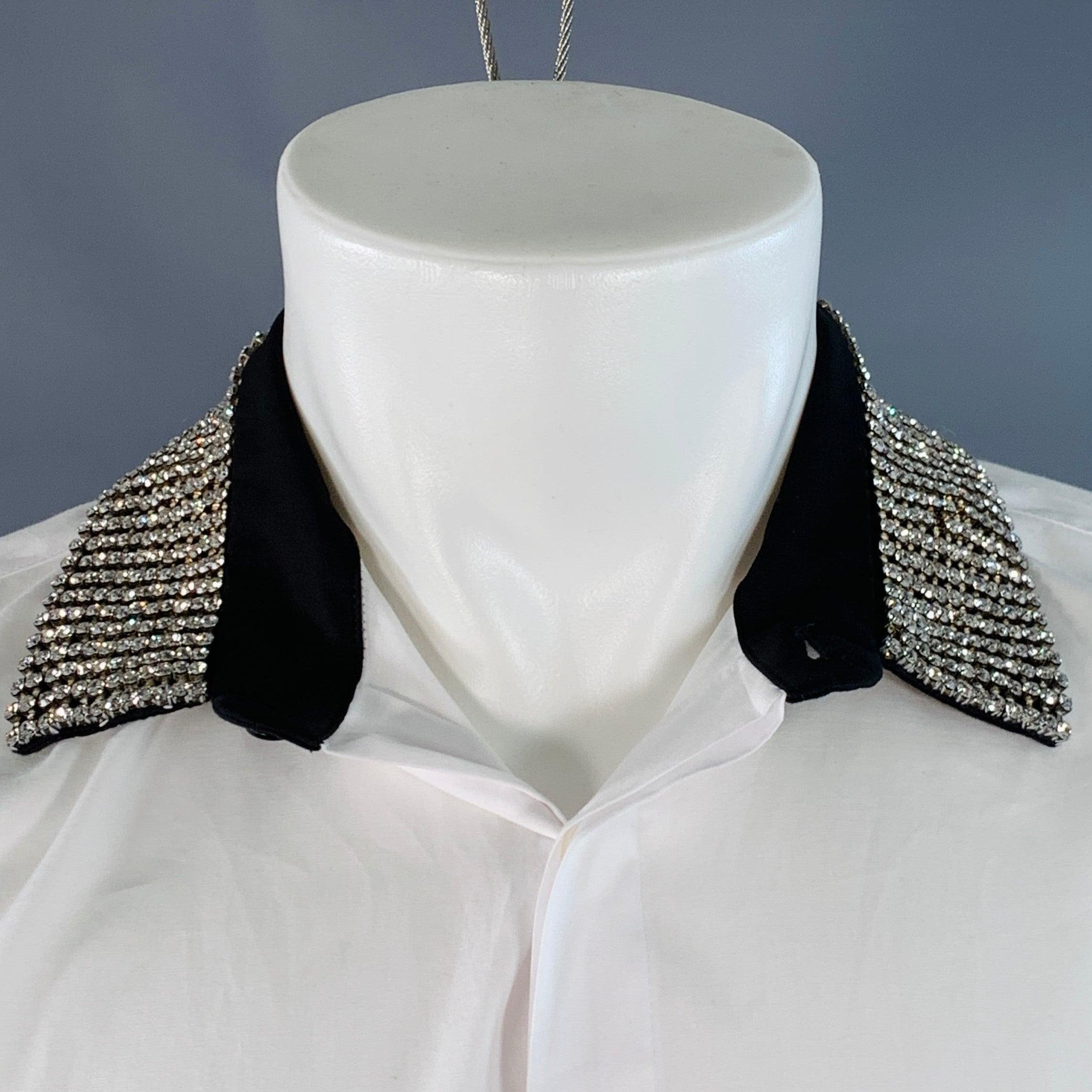 Camisa de manga corta HAIDER ACKERMANN
en tejido de algodón blanco, con cuello tachonado de brillantes y cierre de botón oculto. Buen estado usado. Faltan algunos cristales en el cuello, marca en la manga. 

Marcado:   S 

Medidas: 
 
Hombro 18