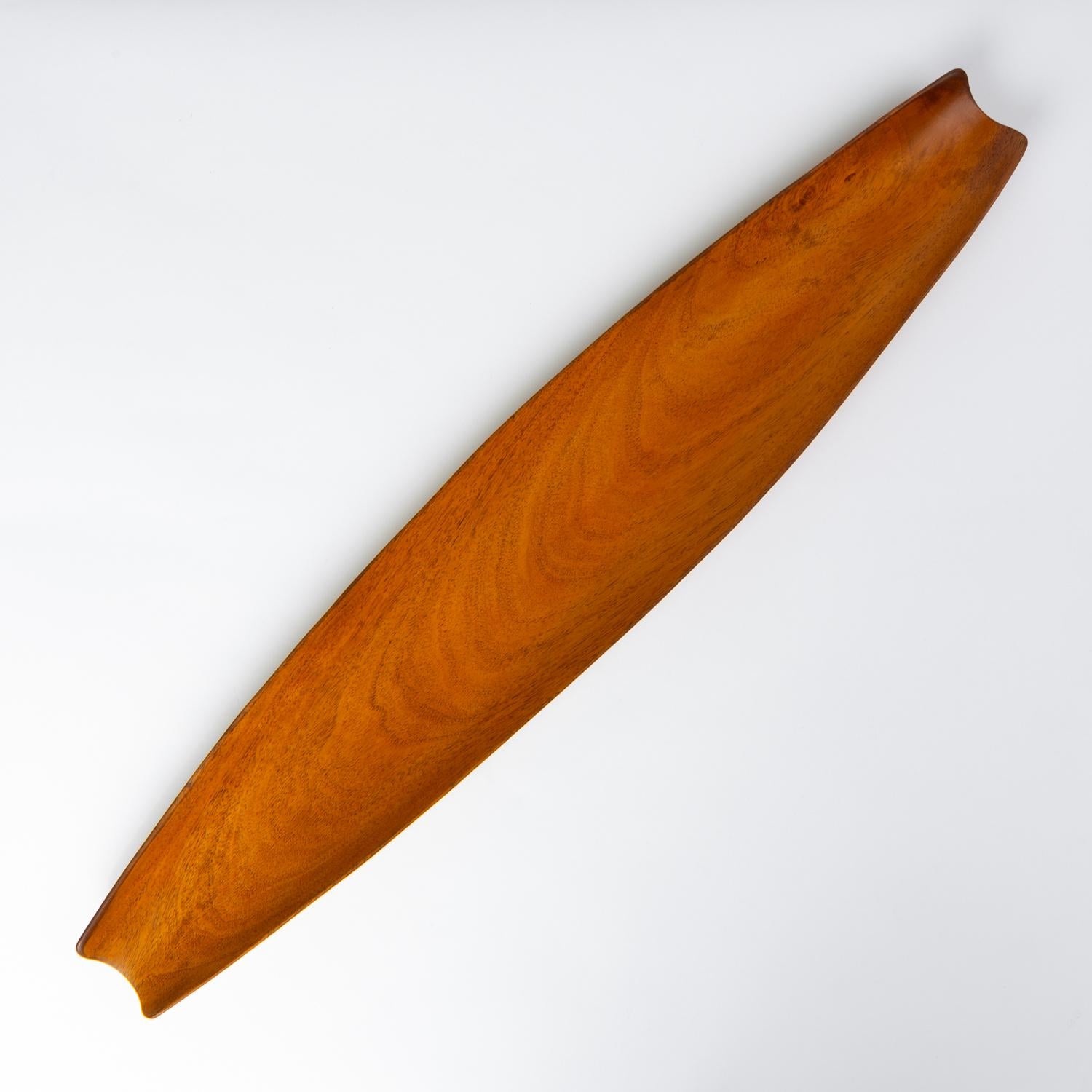 A long, curved wooden bowl from Haitian company, pantalcraft. Handmade on the island from local woods - in this case the material is Taverneau, also known as Caribbean Walnut or False Tamarind, a durable tropical hardwood with a golden hue. The bowl