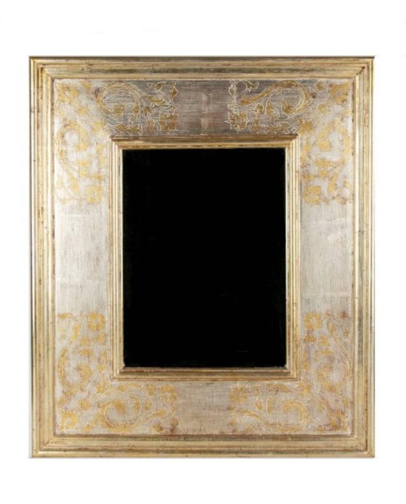 An exceptional, finely crafted hand carved frame with stepped surround and incised foliate scrolled decoration in the corners. The surface with red gesso and applied gilt and silver gilt, with a central mirror. In the style of the noted artists