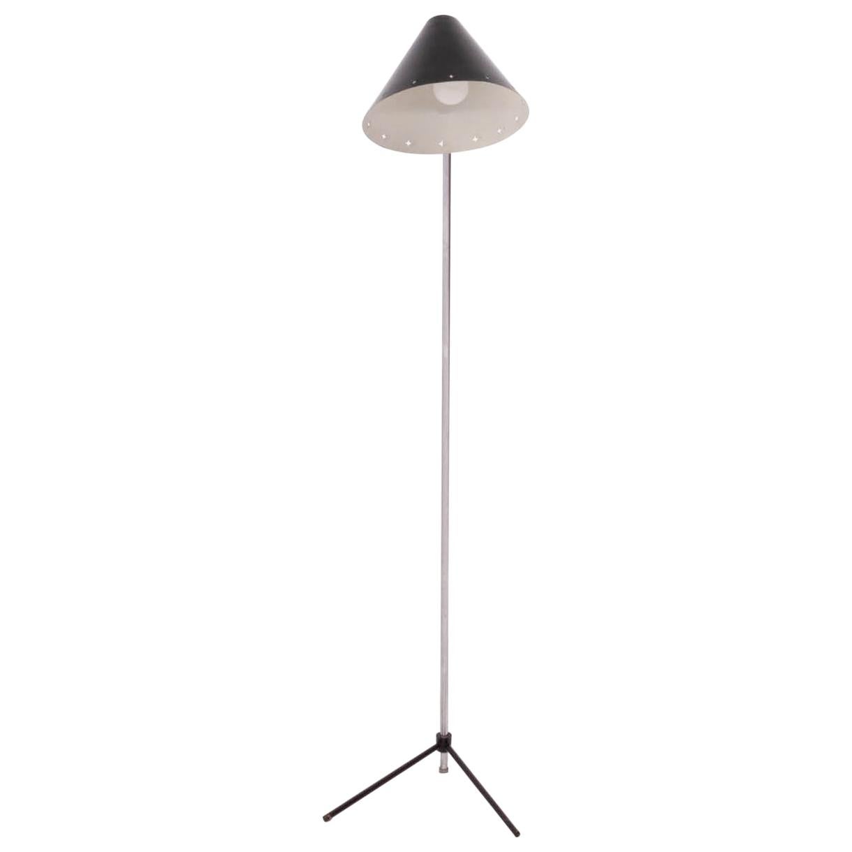 Designed by H. Busquet for Hala Zeist in 1954, this rare Pinocchio floor lamp features a black enamel shade with star-shaped cut-outs around the edge.

The mid century lamp has a metal stand with black angled feet, and can be turned on and off