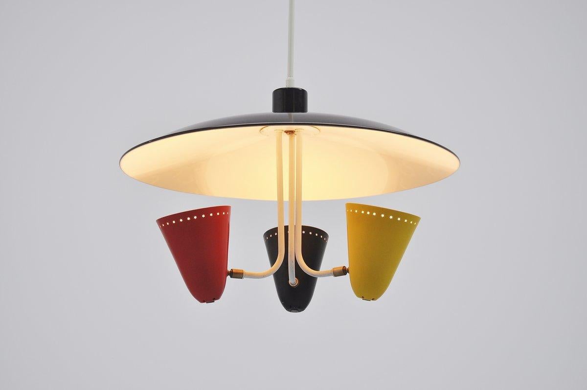 Very nice and typical Dutch 1950s ceiling lamp designed by H. Busquet for Hala Zeist, Holland, 1955. This nicely shaped ceiling lamp has a large black lacquered reflector dish with 3 colored shades underneath in black, yellow and red. The shades are