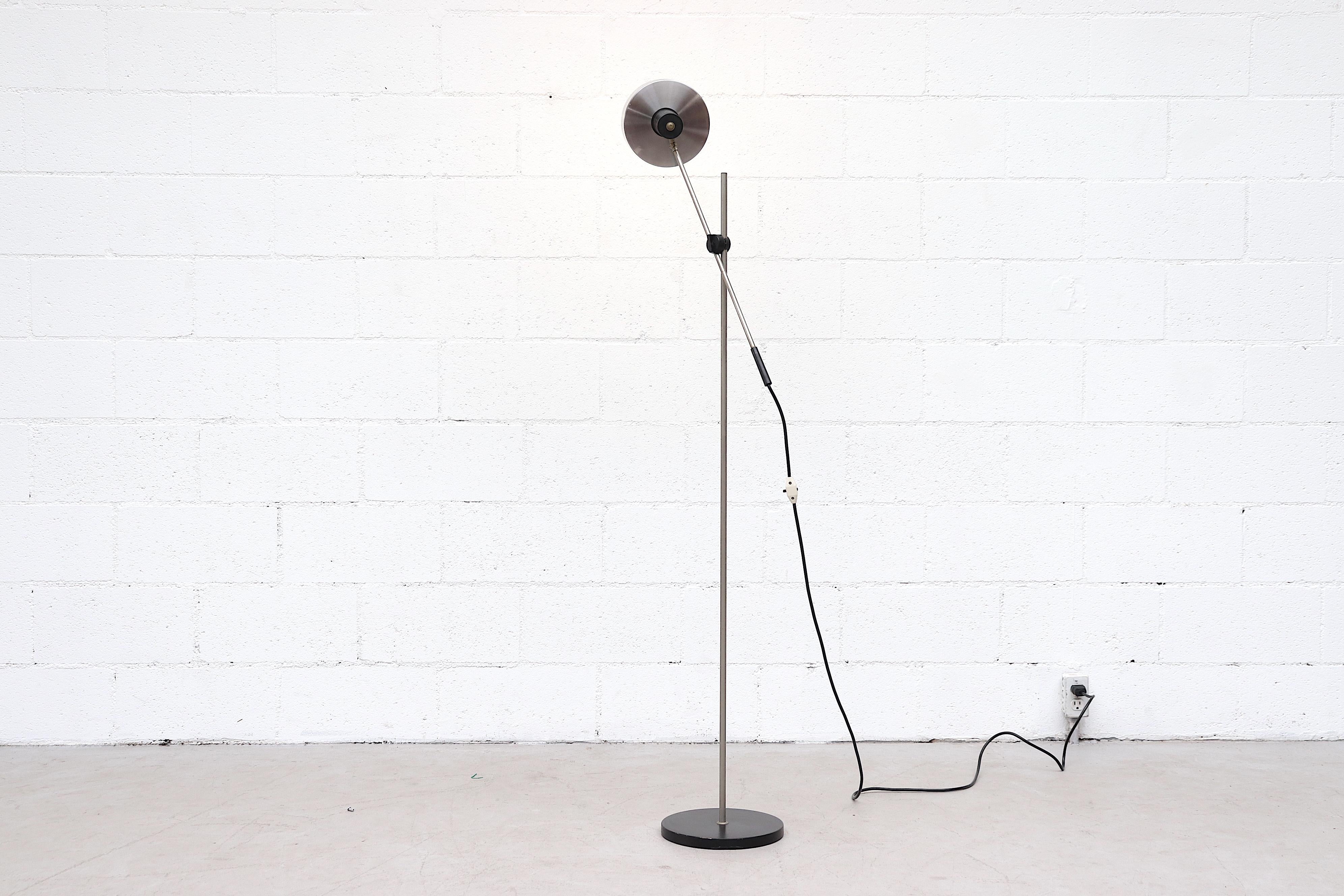 Midcentury cantilevered floor lamp with black enameled metal base and black accents. Adjustable arm, height, and shade for a variety of light configurations. In original condition with visible wear consistent with its age.