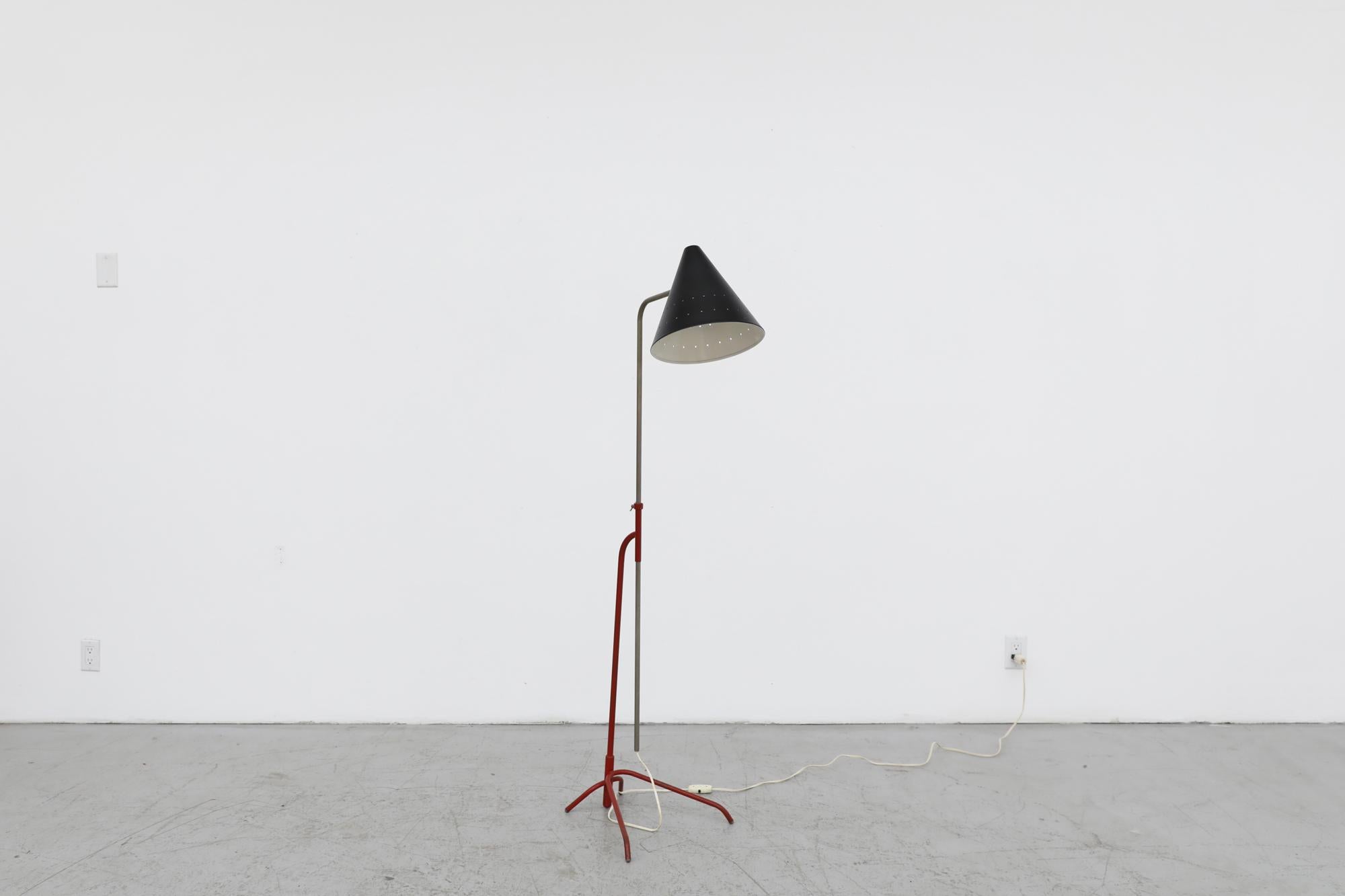 Mid-Century floor lamp with red base, black enameled cone shade and adjustable stem. This lamp is similar in design of the famed Pinocchio Floor Lamp by Hala Zeist. In original condition with visible wear consistent with its age and use. Has