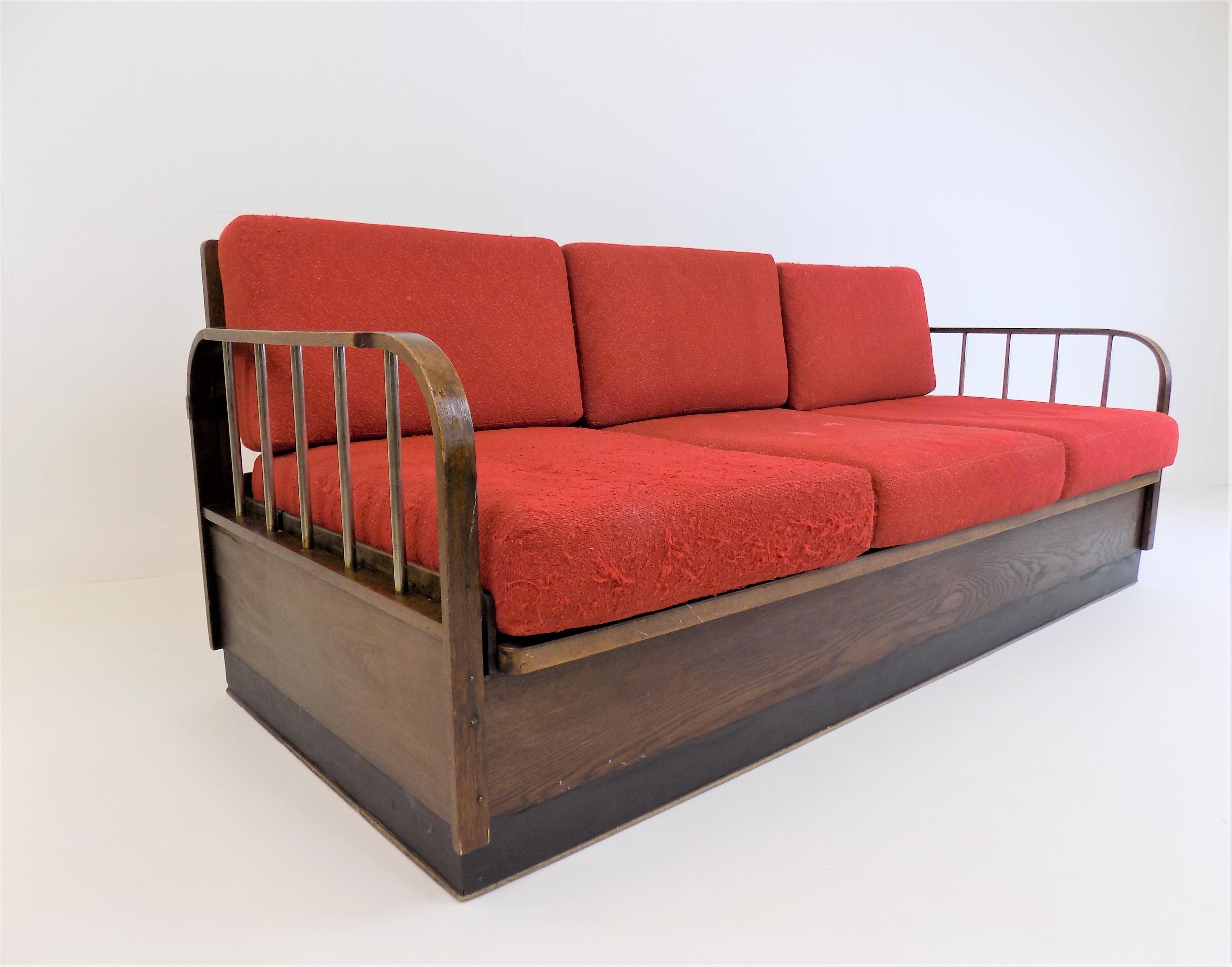 This classic of Bauhaus and Czech functionalism is in good condition. The oak frame shows slight signs of wear. The side panels on this model are finished with chrome bars which have an attractive patina. The bottom of the sofa under the seat