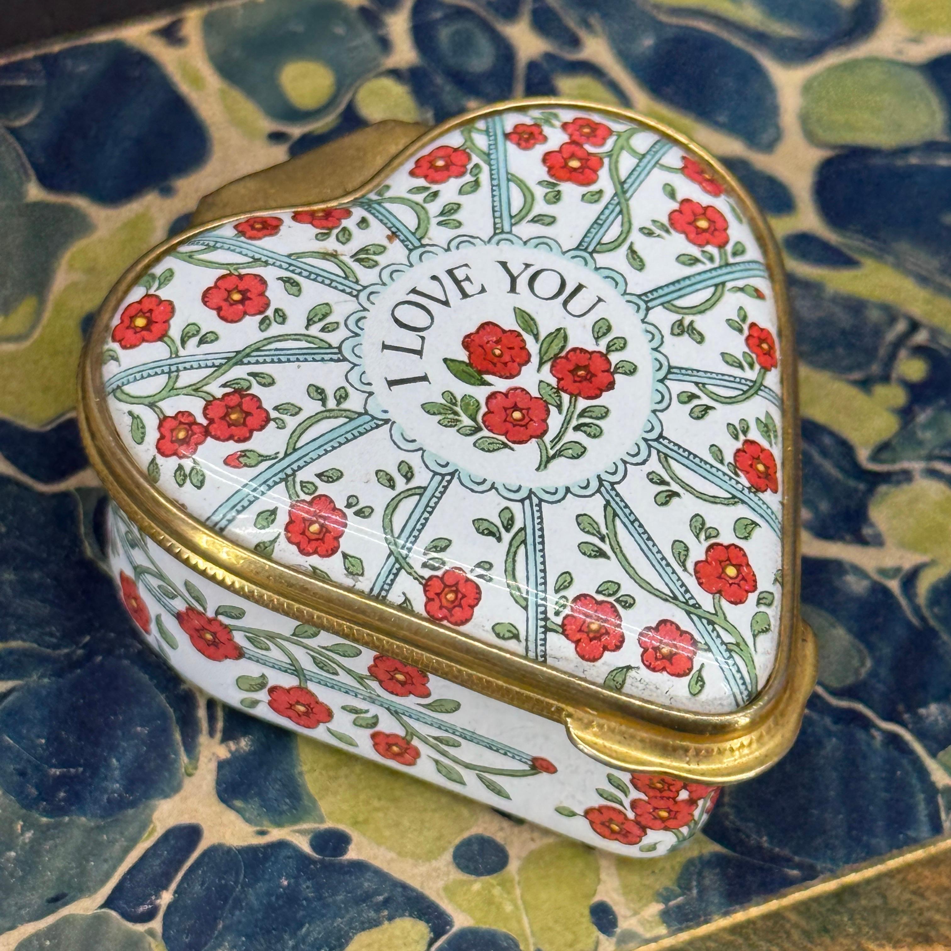Charming trinket, pill or small jewelry box in the shape of a heart. Text reads I Love You, surrounded by flowers. This piece would certainly be a fantastic addition to an existing collection of these desirable small boxes.


