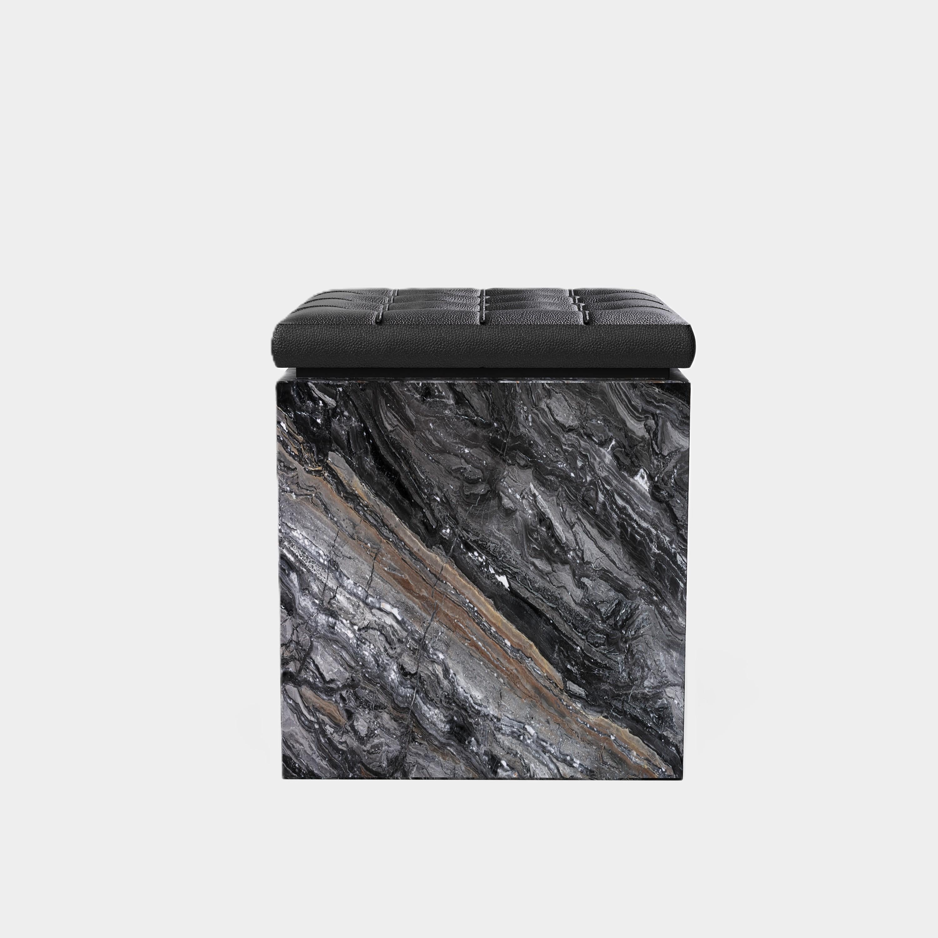 Eine moderne Ottomane mit einem schön getufteten Lederkissen auf einem hochwertigen Sockel aus Naturmarmor. Die Oberseite der Ottomane besteht aus einem schwarzen Lederkissen mit klassischem Tufting-Design, das eine weiche und zarte Textur aufweist