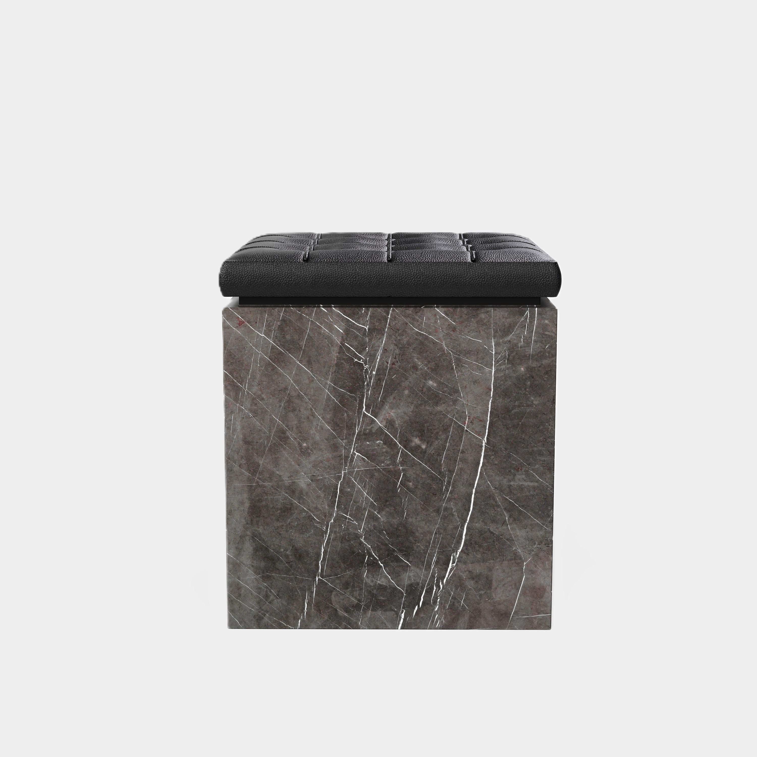 Eine moderne Ottomane mit einem schön getufteten Lederkissen auf einem hochwertigen Sockel aus Naturmarmor. Die Oberseite der Ottomane besteht aus einem schwarzen Lederkissen mit klassischem Tufting-Design, das eine weiche und zarte Textur aufweist