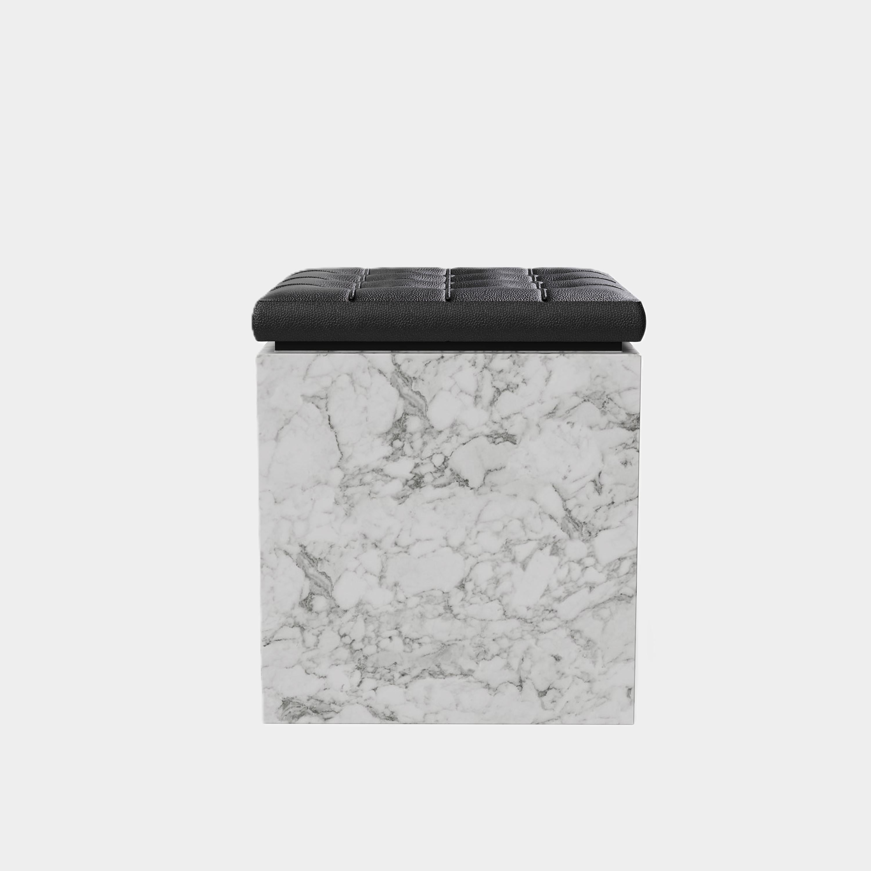 Un pouf contemporaneo con un cuscino in pelle splendidamente trapuntato su una base a zoccolo in marmo naturale di alta qualità. La parte superiore del pouf presenta un cuscino in pelle nera, con un classico disegno a ciuffi che offre una texture