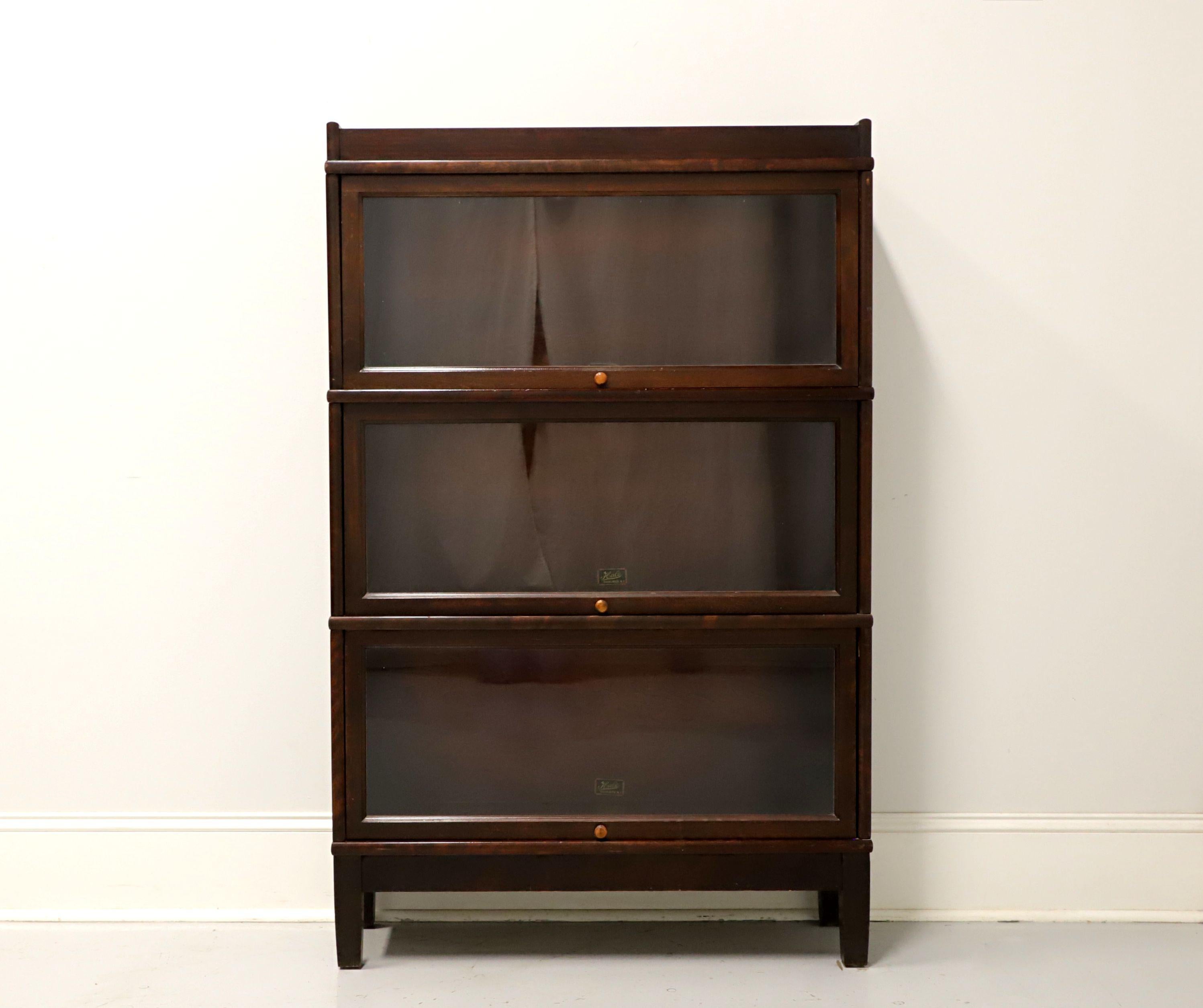 An Arts & Crafts style stacking barrister bookcase by Hale of Herkimer, New York, USA. Mahogany with wood knobs and metal slide mechanisms. Features crown, three stacking flip up slide back glass door bookcase units and base with straight legs. Each