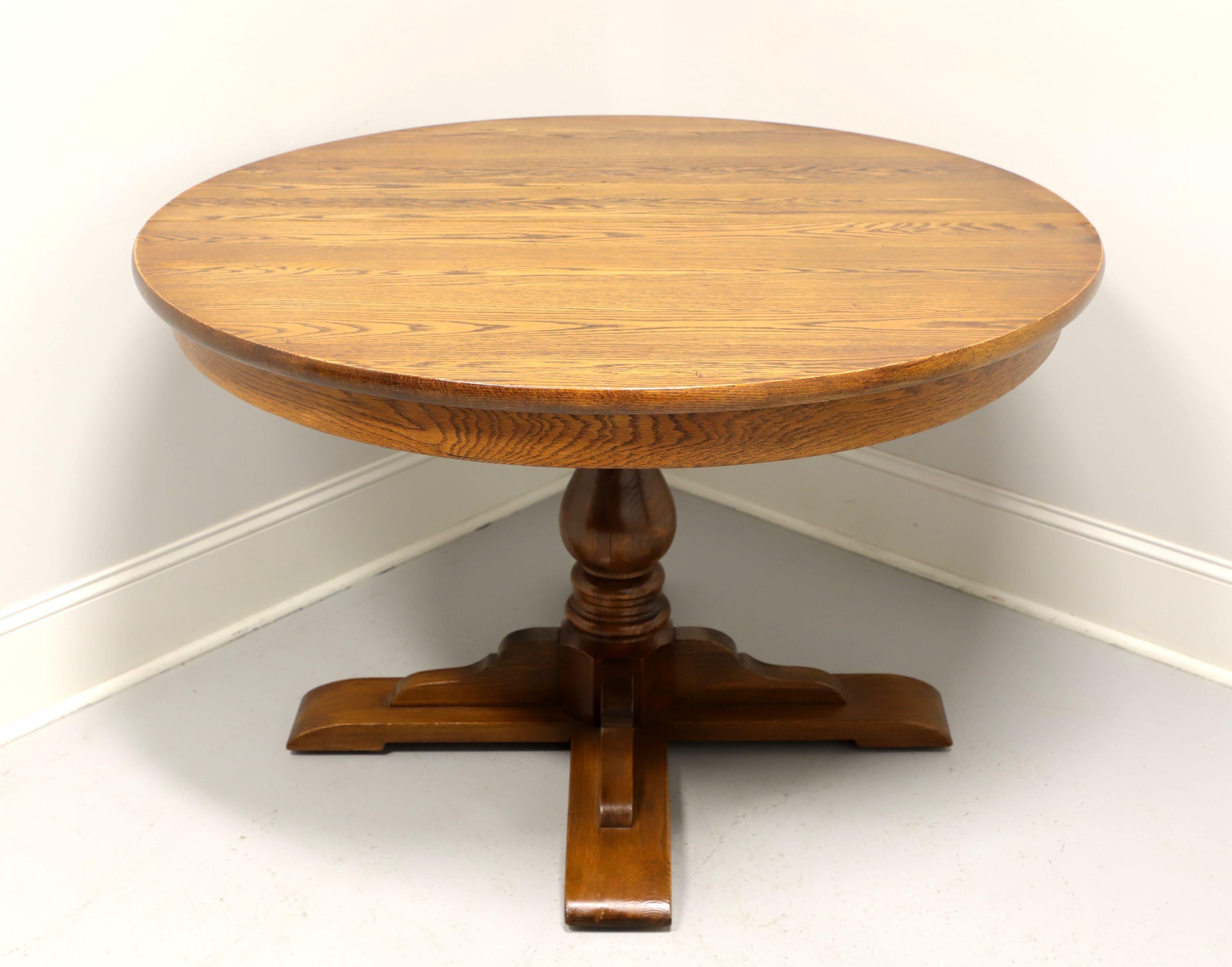 A vintage Rustic style round dining table by Hale Furniture of East Arlington, Vermont, USA. Solid oak, smooth apron, turned pedestal base with four bracket legs on flat bracket feet. Wood expansion slider. Includes two extension leaves that make