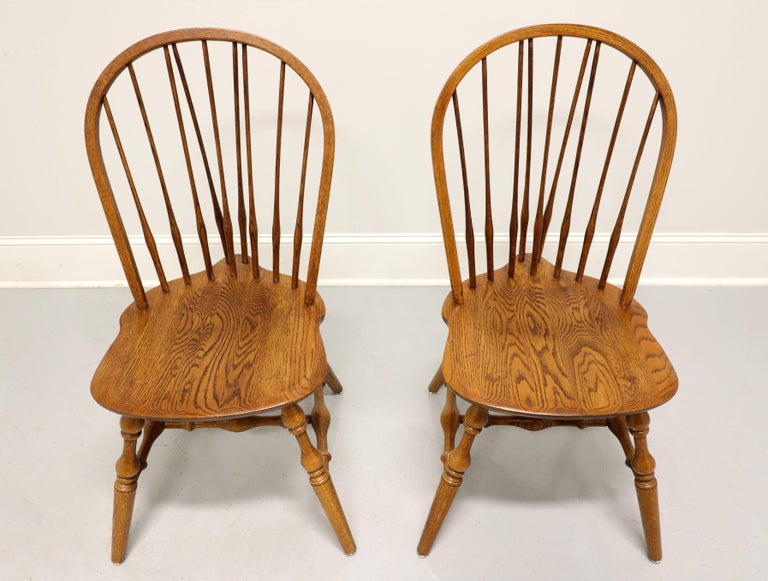 A pair of Windsor style dining side chairs by Hale Furniture of East Arlington, Vermont, USA. Solid oak, hoop back with spindles, saddle shape seat, tail-supports with spindles, turned legs and stretchers. Made in the mid 20th century.

Measures: