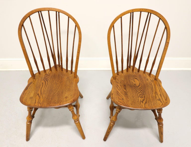 A pair of Windsor style dining side chairs by Hale Furniture of East Arlington, Vermont, USA. Solid oak, hoop back with spindles, saddle shape seat, tail-supports with spindles, turned legs and stretchers. Made in the mid 20th Century.

Measures: