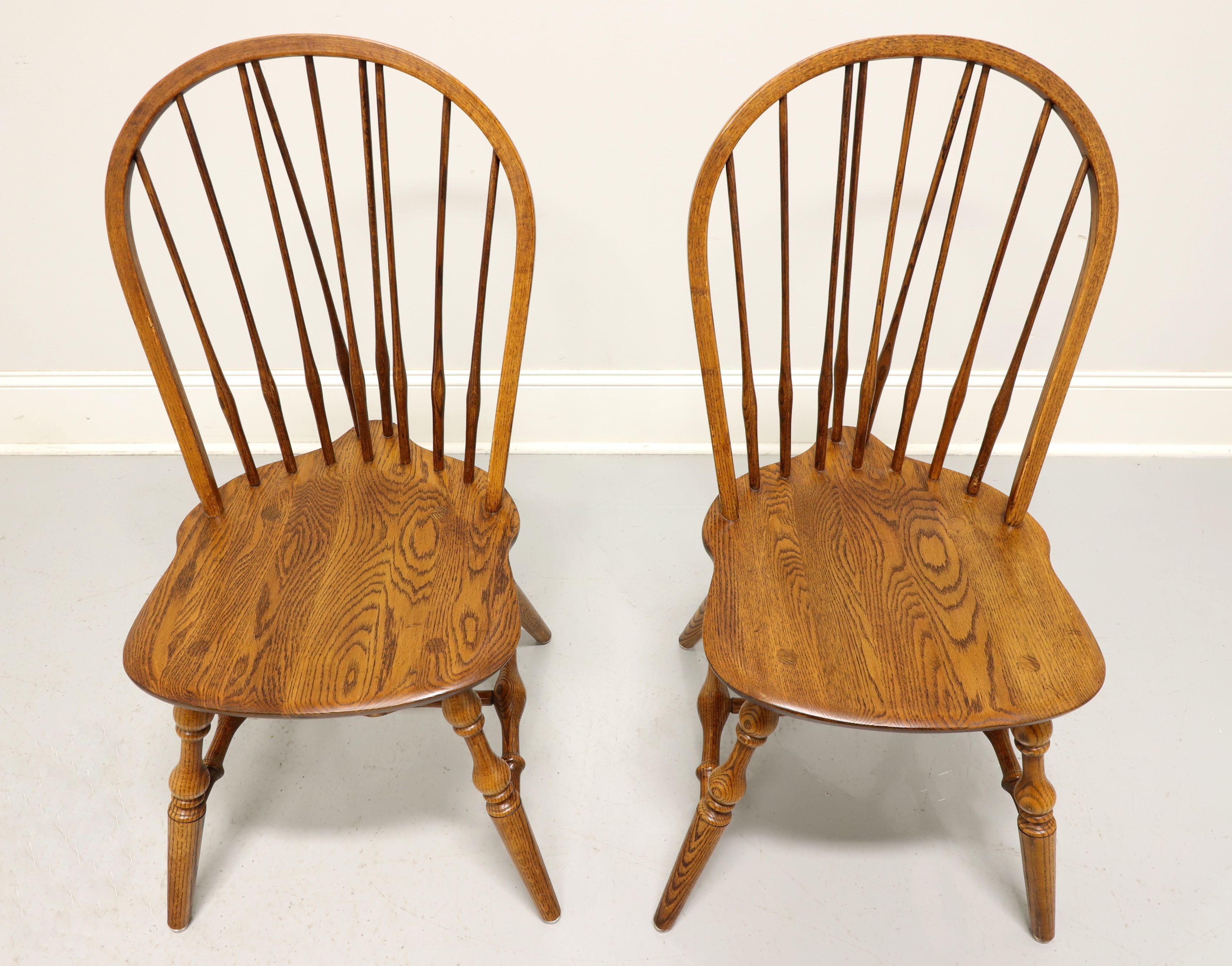 A pair of Windsor style dining side chairs by Hale Furniture of East Arlington, Vermont, USA. Solid oak, hoop back with spindles, saddle shape seat, tail-supports with spindles, turned legs and stretchers. Made in the mid 20th Century.

Measures: