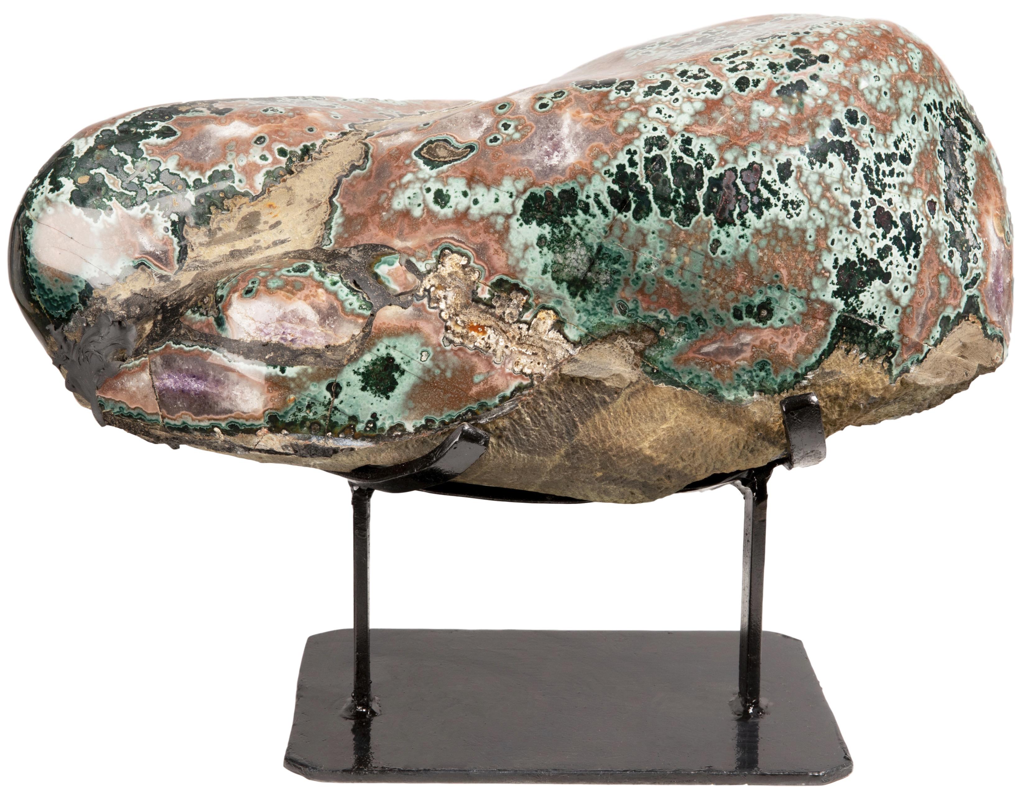 This is an extraordinary half geode with a calcite formation. This piece celebrates the visual phenomenon of the geode interior with some parts of the sculpture being rough basalt, and others showcasing combinations of amethyst, green celadonite,