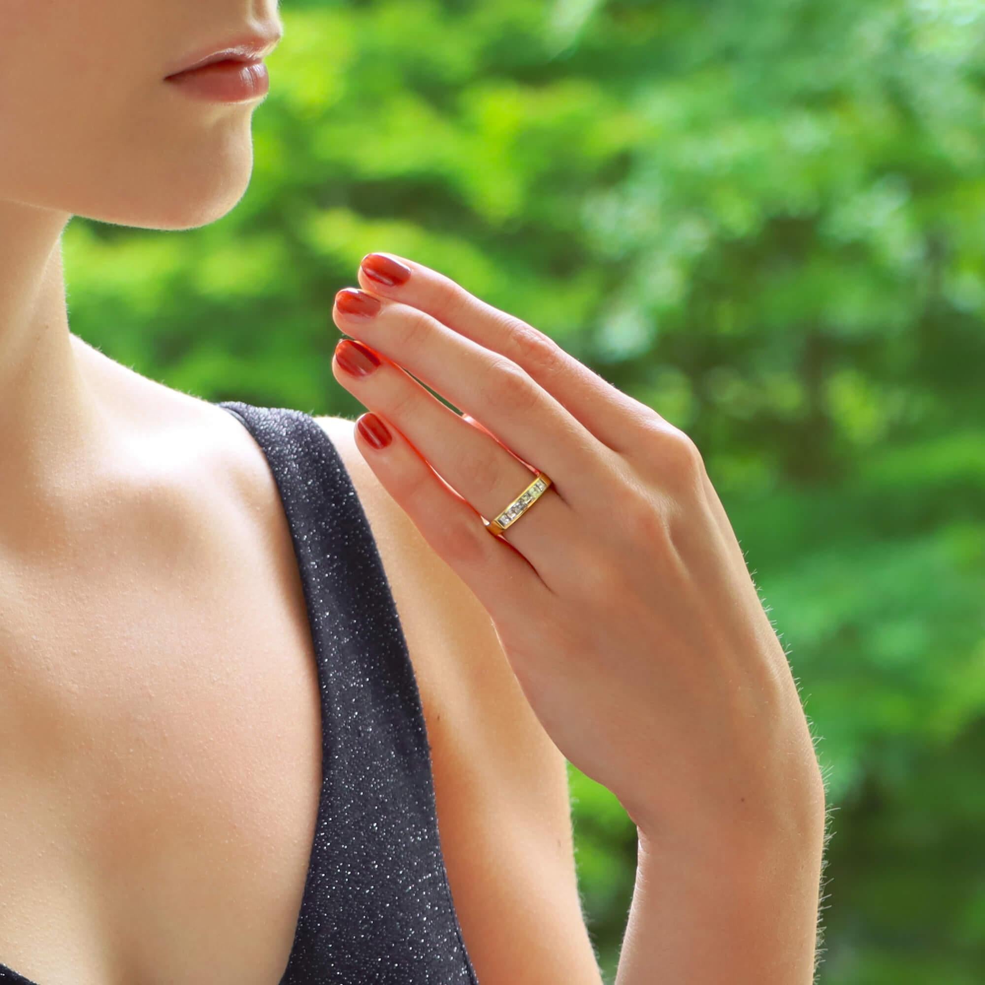 Ein schmeichelhafter Halbdiamant-Ewigkeitsring aus 18 Karat Gelbgold. Dieser Ring ist mit sechs stufenförmig geschliffenen Diamanten in Kanalfassungen auf der Vorderseite besetzt, mit polierten Rändern und einem massiven Goldband.

Ungefähres