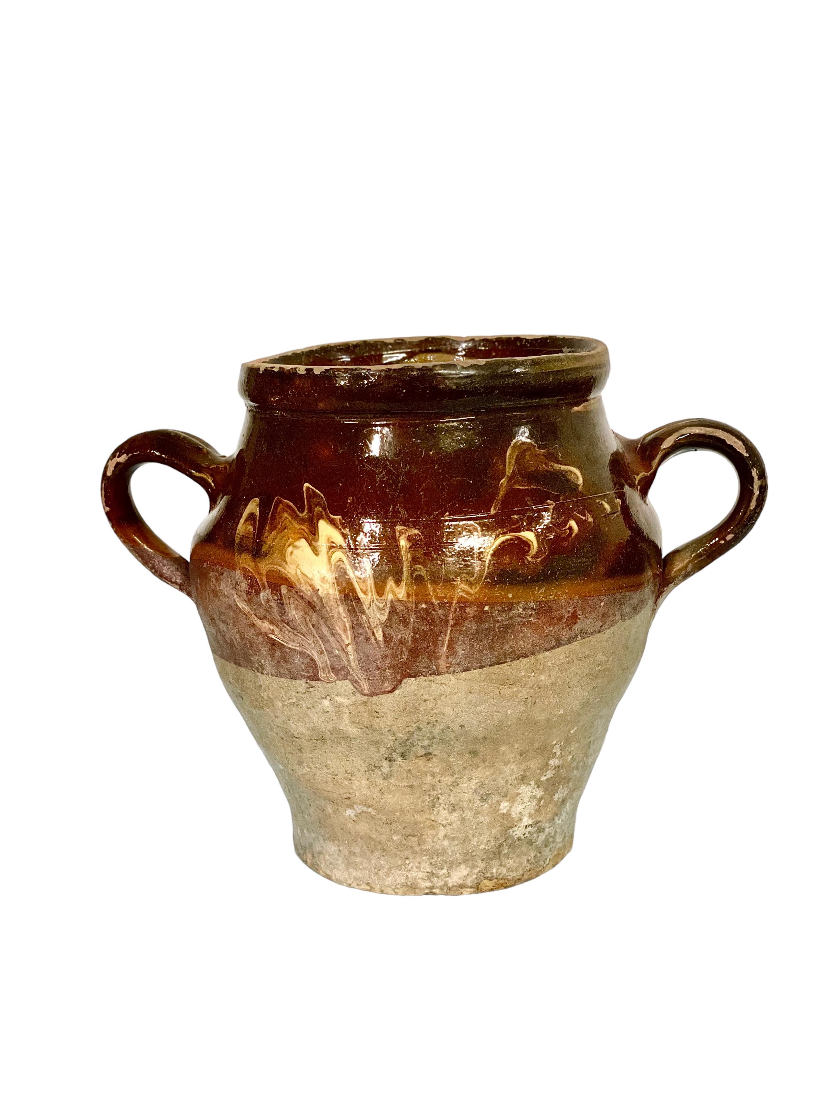 Traditional French terracotta confit pot with two side handles. Half glazed in brown with a 'flame' design, this vessel would have been used to conserve food – mainly meats in fat – before the invention of refrigeration. It's unglazed portion