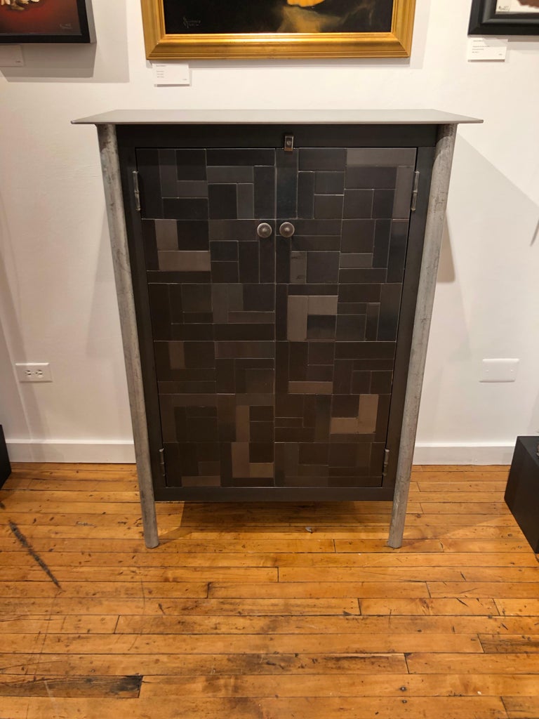 This totally functional modern industrial cabinet is created from recycled hot-rolled steel. The monochromatic quilt pattern in the doors and on the sides of the piece are inspired by quilt patterns. The interior of this cabinet contains two fixed