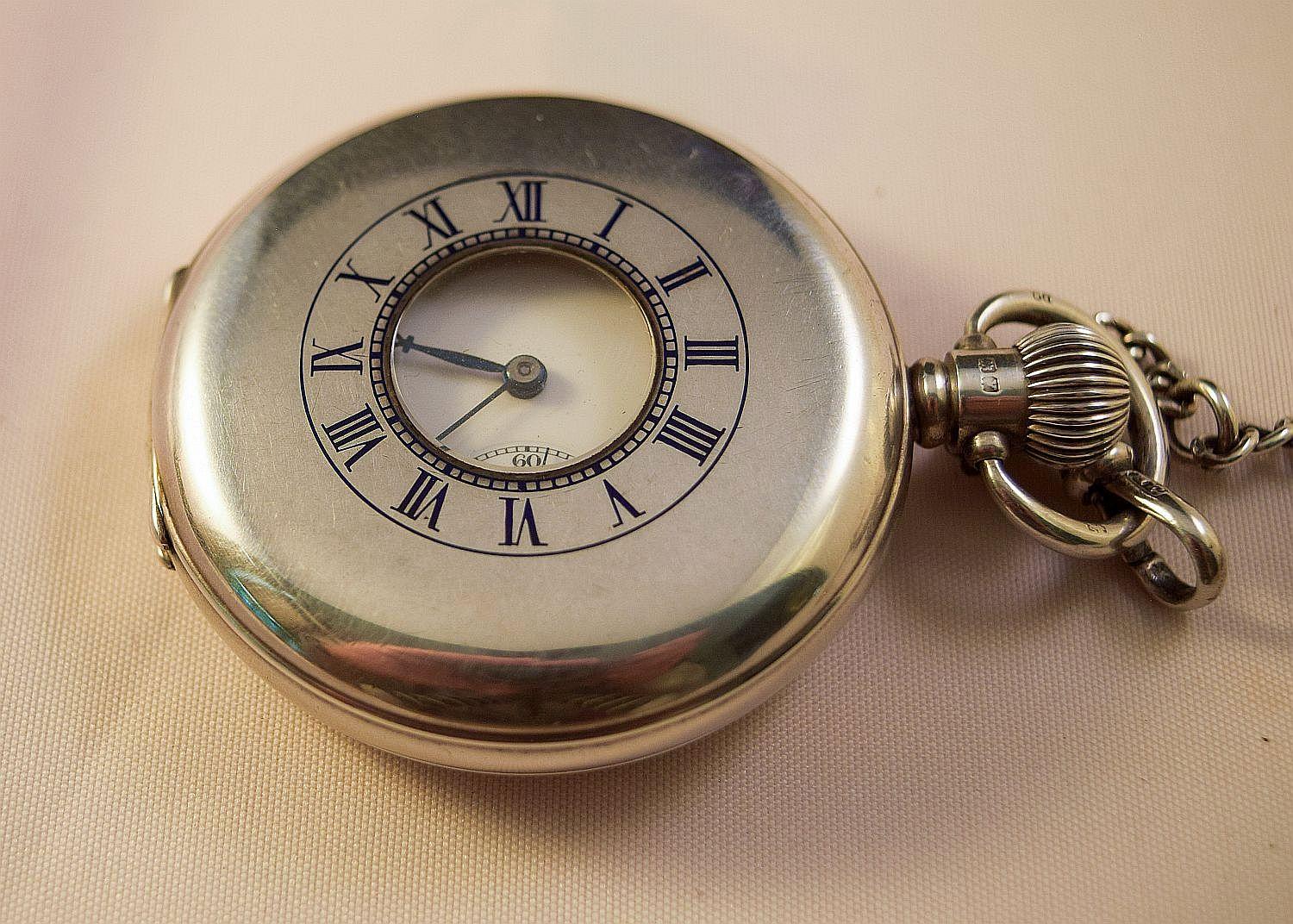 Half Hunter early 20th century Gents Silver pocket watch.
Having  black enamel Roman number markings,circular white attractive enamel dial 
with bold and thick beautiful Roman numerals and sub seconds at 6.
Movement signed Swiss Made 2 adjusts 15