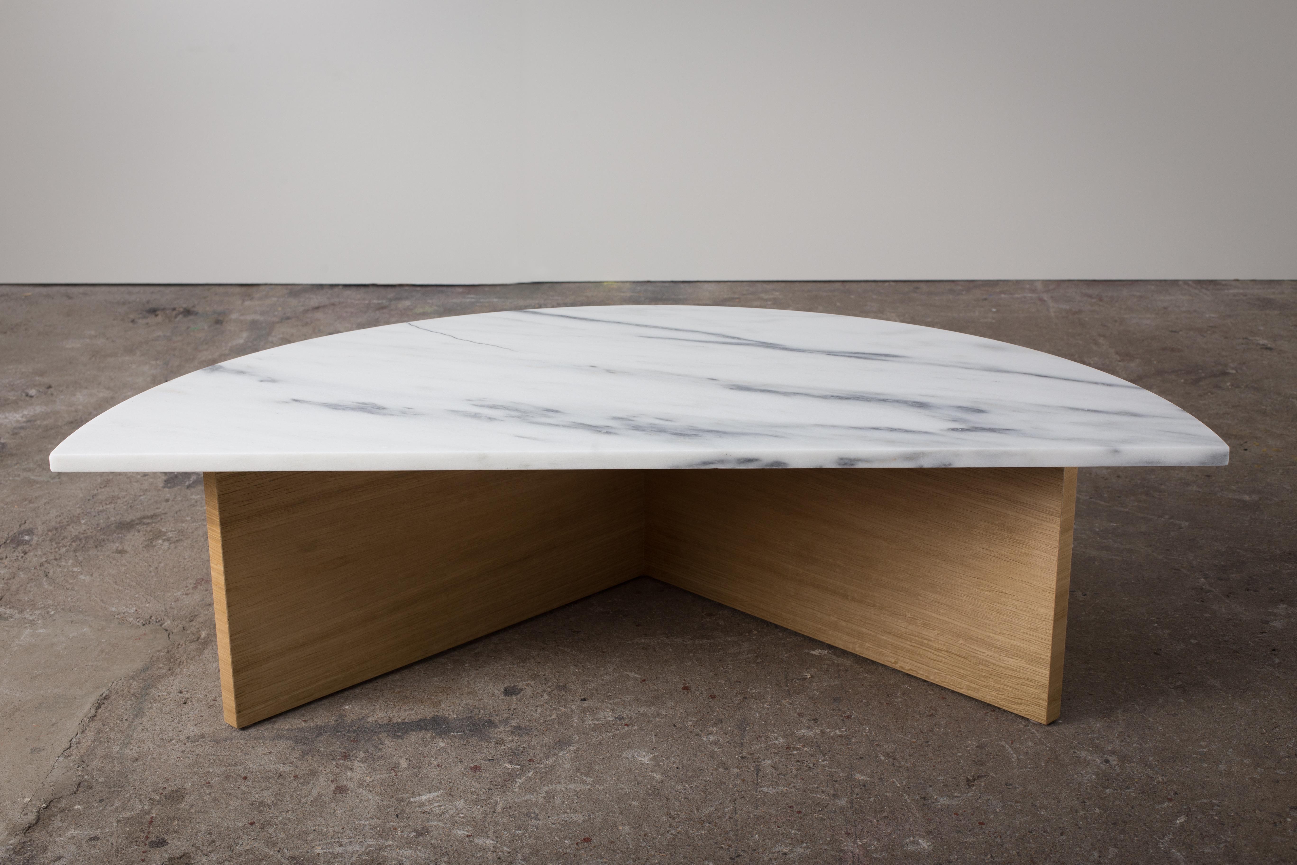 A distinctive coffee table consisting of two separate halves that are placed together to create dynamic spacing in the center of the table. With a white oak base and honed marble top, the design highlights the beauty of the natural materials through