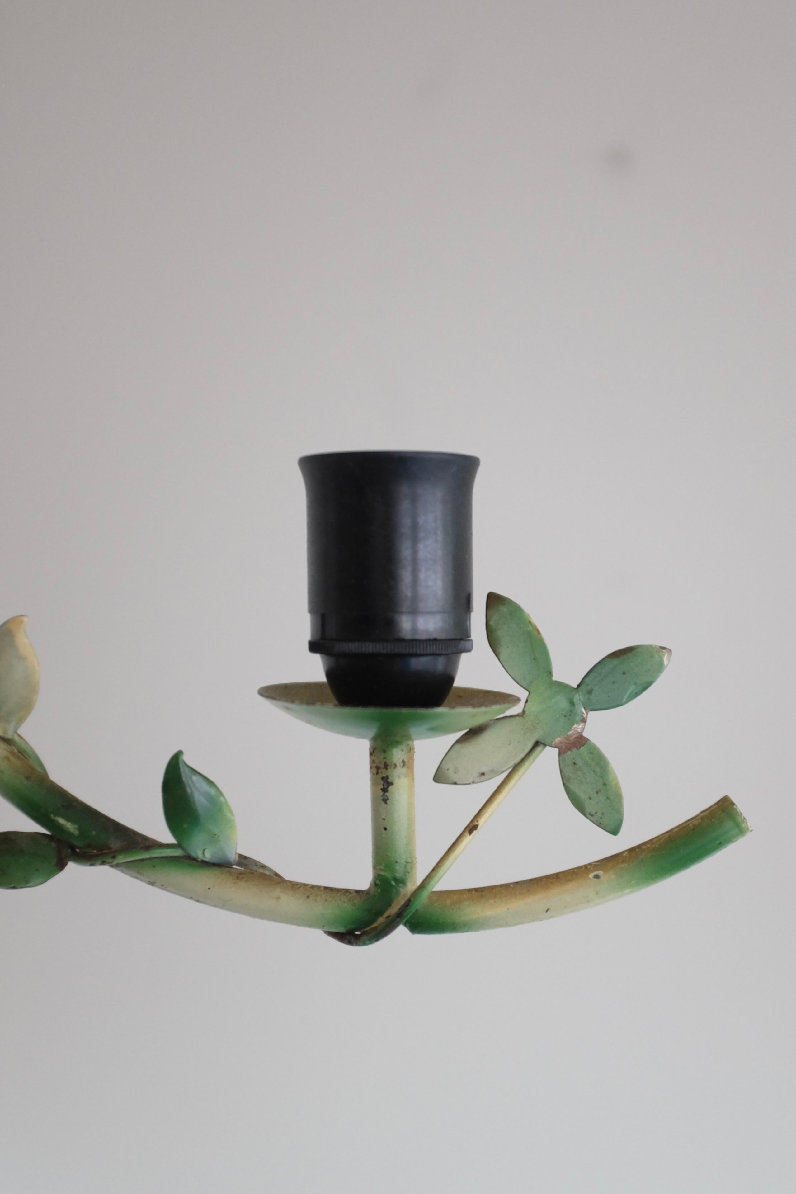 Pendente da esterno svedese vintage degli anni '50 in metallo con ornamenti a forma di foglia nei colori verde e crema. L'ornamento a forma di foglia corre lungo la mezzaluna del ciondolo con un fiore ad ogni estremità. Il baldacchino ha un bordo