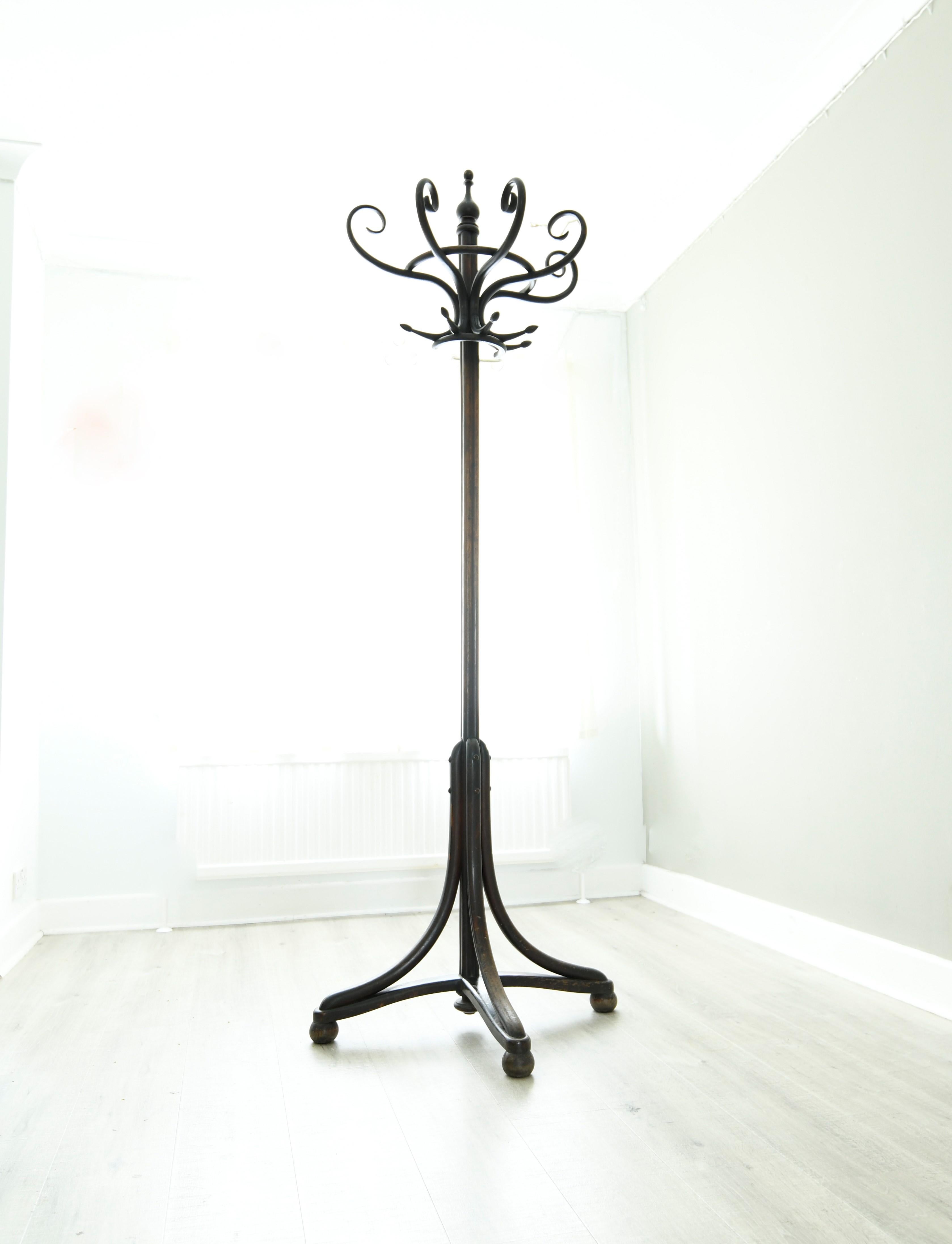 A Thonet Art Nouveau half round bentwood coat and hat stand or hall stand, having five coat hooks and five bentwood scrolls for hats, makes this a very rare piece. Its surmounted by a finial, supported on cluster column terminating in three