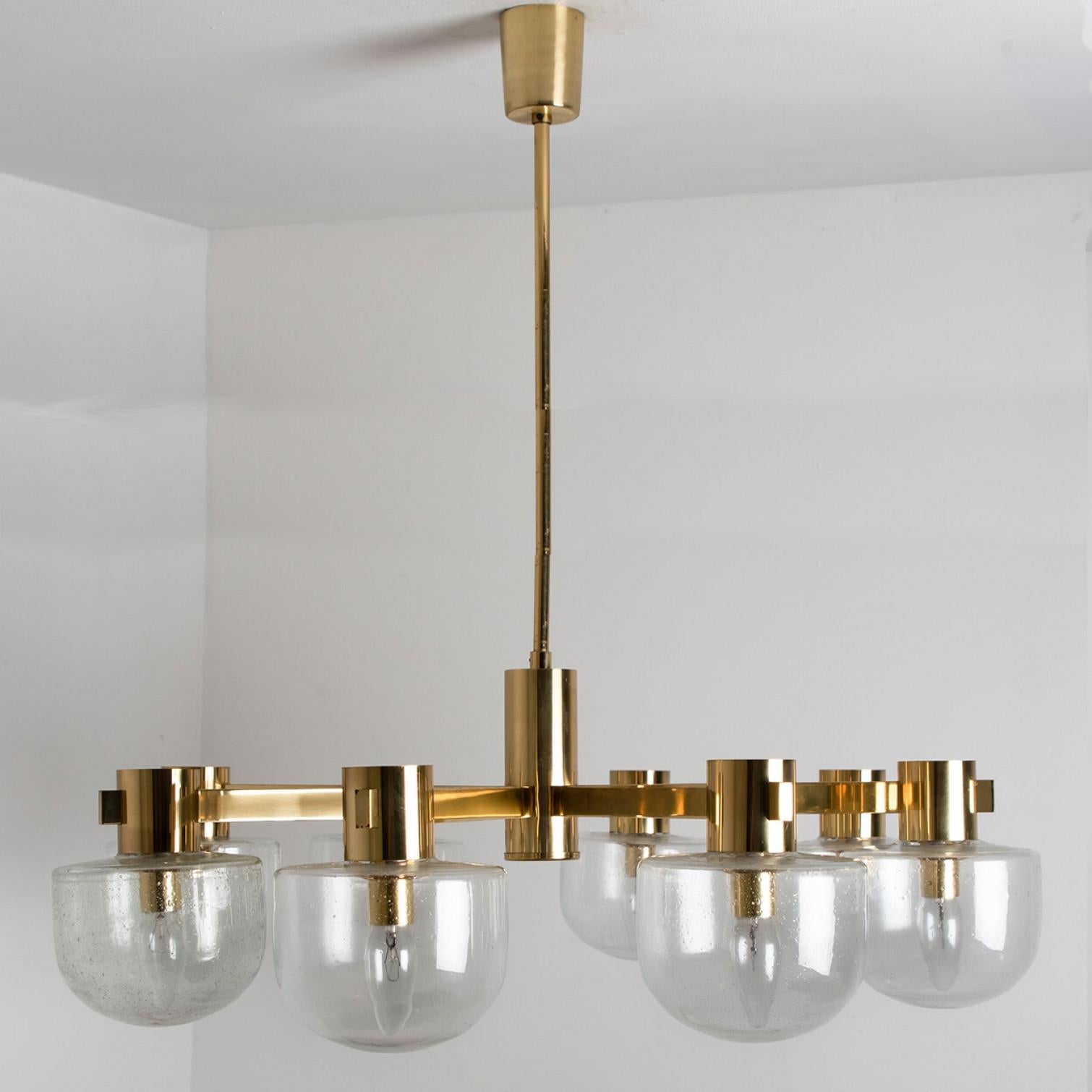 Beautiful chandelier by Hillebrand. Manufactured in Germany, circa 1960.
With beautiful glass shades and gold details on a gold mounting hardware. The chandelier shows 8 arms, each with an clear white glass shade. This chandelier illuminates