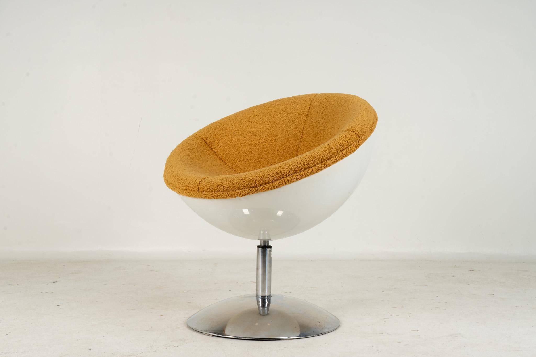 This playful 1970s pod chair swivels on a polished chrome base. The back of the pod is made from resin and the seat has been newly reupholstered in boucle. The plastic resin back is in overall good condition with a few scratches. The chrome bases