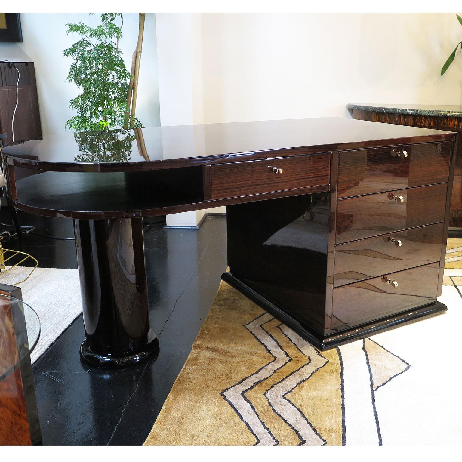 French Art Deco desk featuring a curved end with round pedestal leg. The other end featured a square pedestal leg with four drawers for storage. There is a pencil drawer in the center as well as an open shelf space by the curved pedestal base. Done