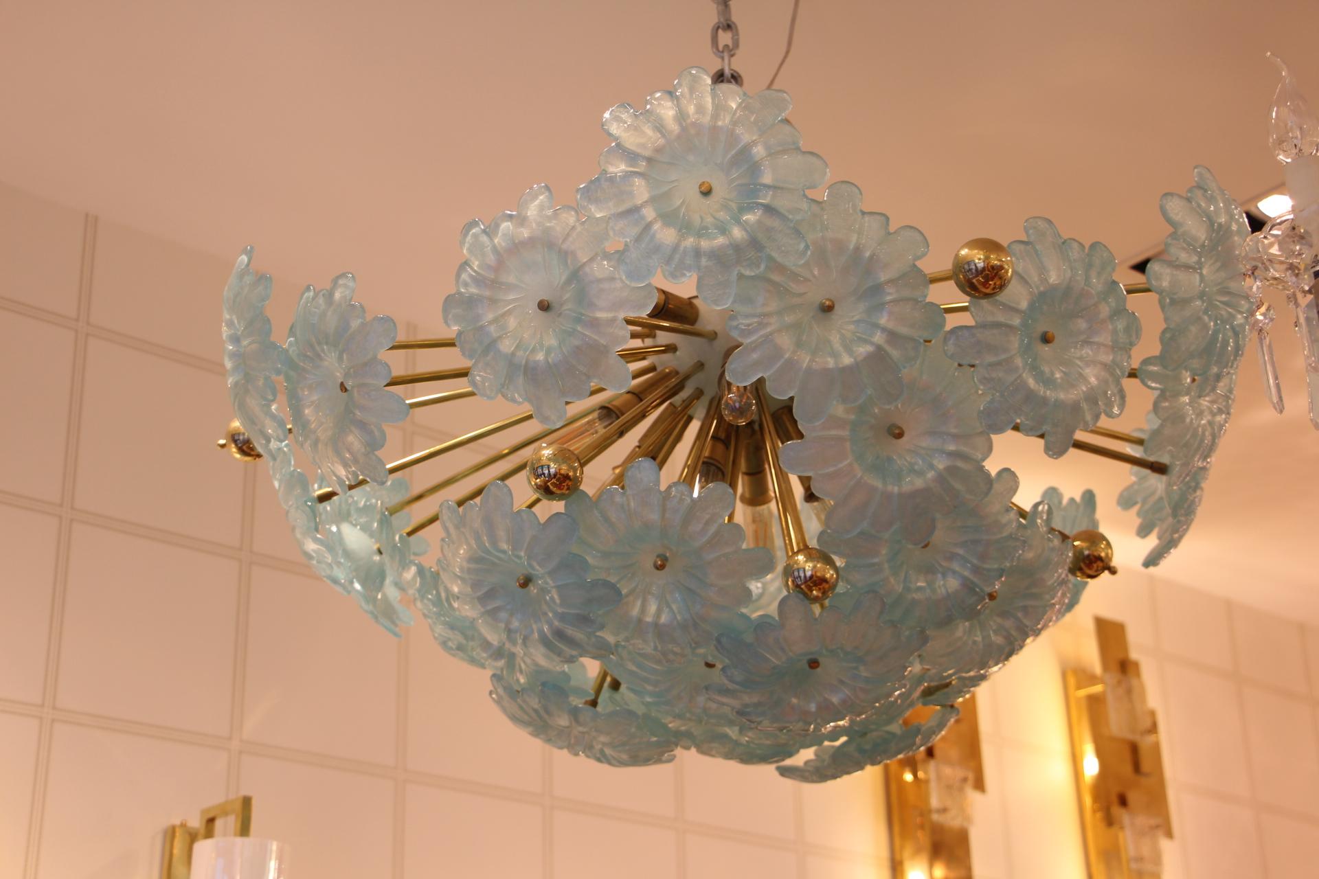 This very unusual half Sputnik chandelier features a multitude of brass rods, some ending with brass balls and others ending with large blue flowers in Murano glass.
All the rods have got different length so that flowers are on different levels and