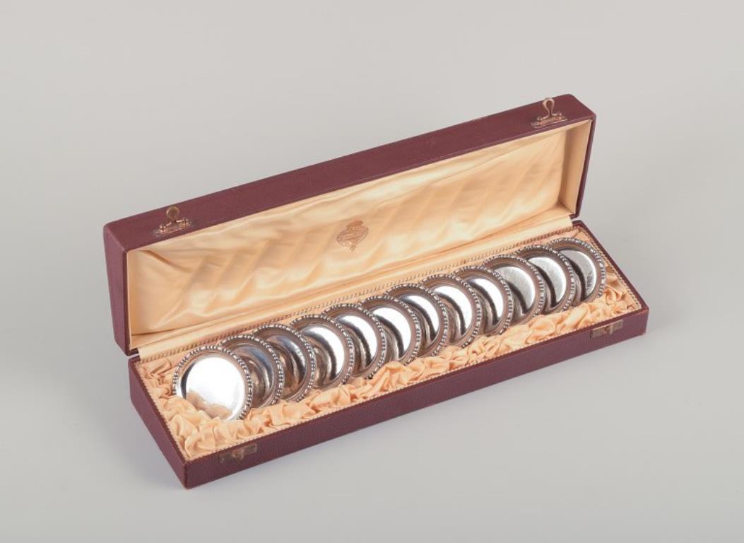 Hallberg, Estocolmo, Proveedor de la Corte Real Sueca. 
Juego de doce posavasos de plata 830. Art Déco.
Sello de fecha A8 = 1927.
Hallmarked.
En perfecto estado.
Caja de regalo original.
Dimensiones: Diámetro 6,2 cm.