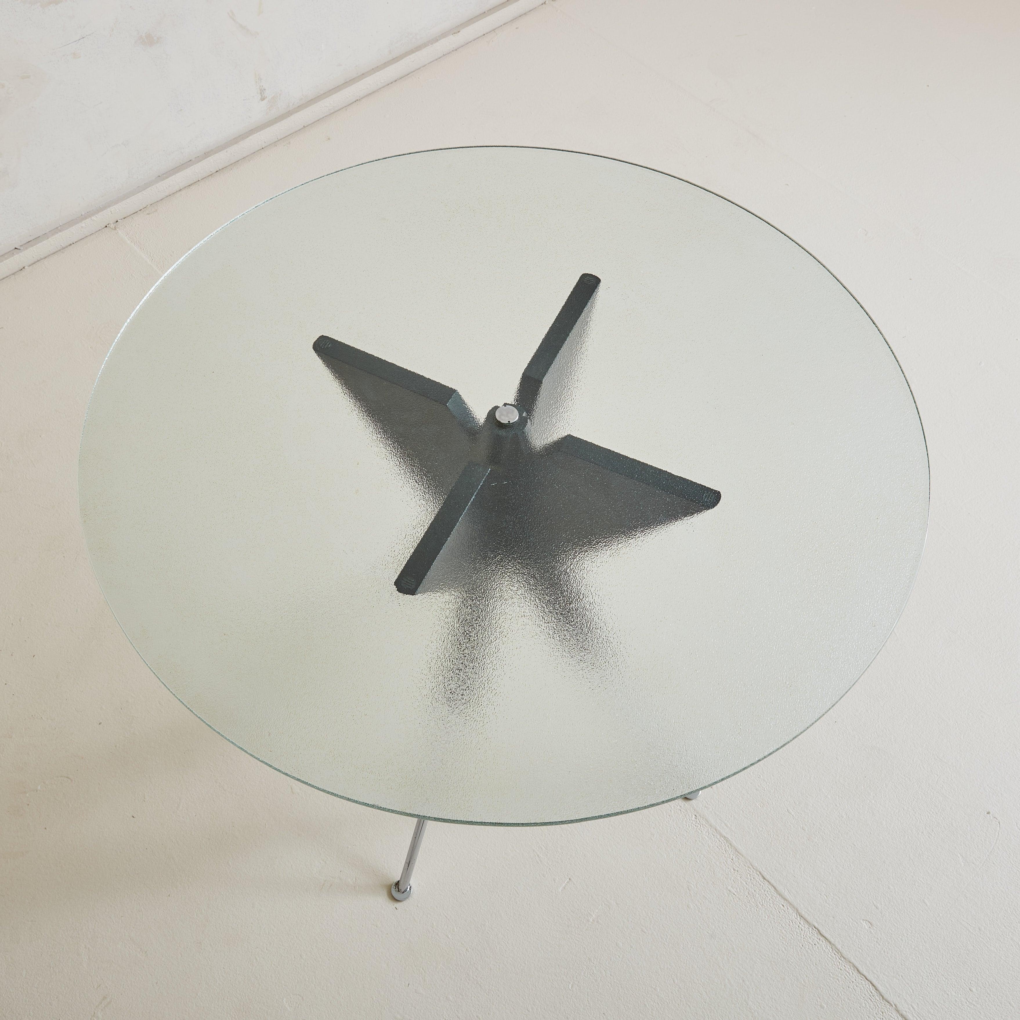 A Spanish ‘Halley’ table designed by Vincent Martinez (b.1949) for Punt Mobles in 1986. This table has a geometric black painted wood tripod base and tubular chrome legs with petite ball feet. The circular, patterned frosted glass tabletop attaches