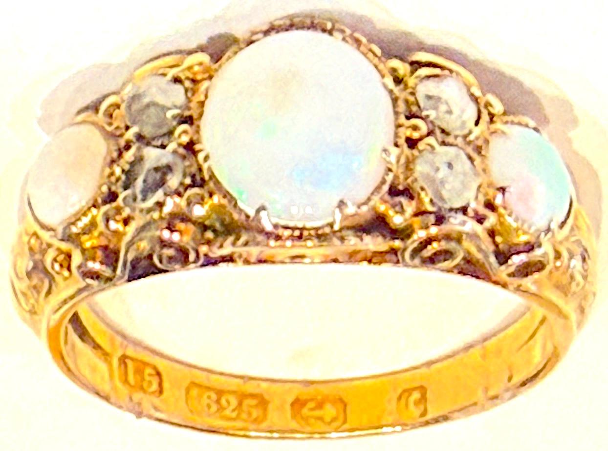 This ring is a classic Victorian 15K,  3 stone carved half hoop design with claw set opals assayed in Birmingham, England,  1877.  The ring spotlights three well matched glowing opals with variegated hues of red, green, blue and yellow.  Between the