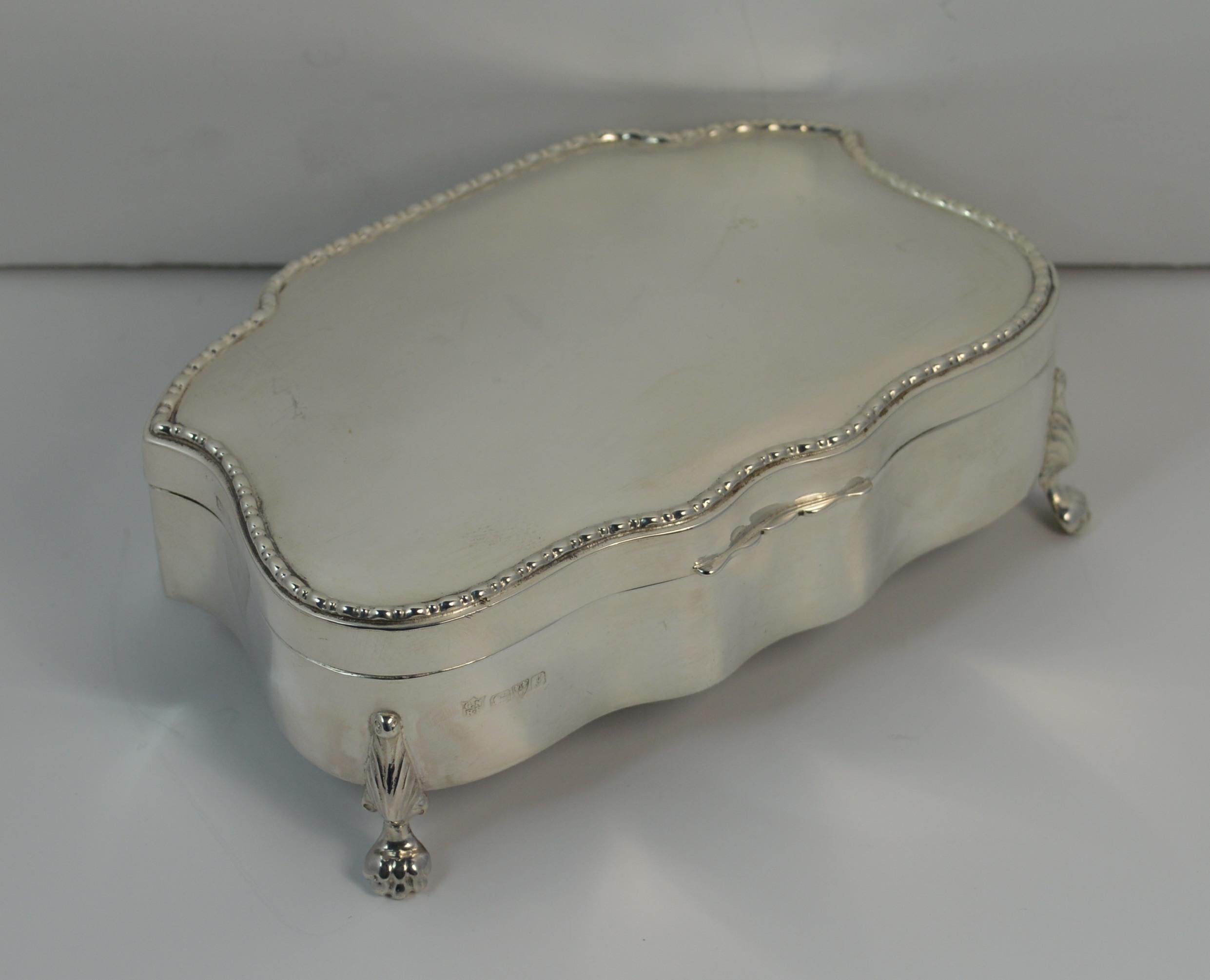 A beautiful English made solid silver jewellery box.
Stylish shape with plain sides and lid and of waved shape. Standing on four feet.
Original insides with six slots for rings and a plain front section for earrings, chains, pendants etc

Hallmarks