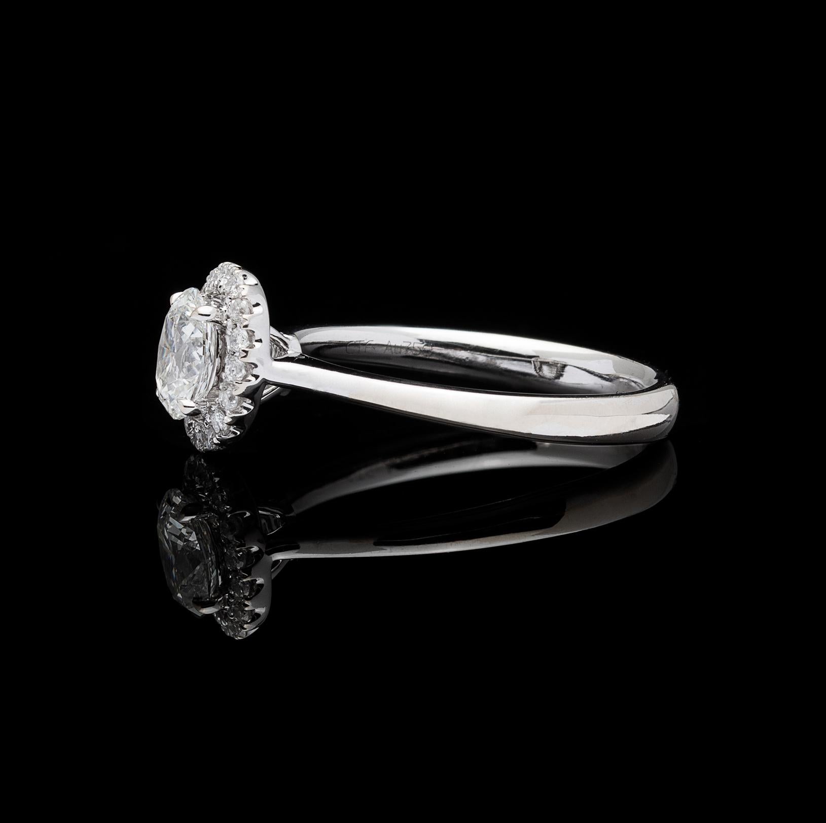 Delicate and feminine, this 18k white gold engagement ring centers a 0.55-carat oval-cut diamond, set within a halo of 16 round brilliant-cut diamonds, for a total diamond weight of approximately 0.71 carats. The ring weighs 2.9 grams, and is