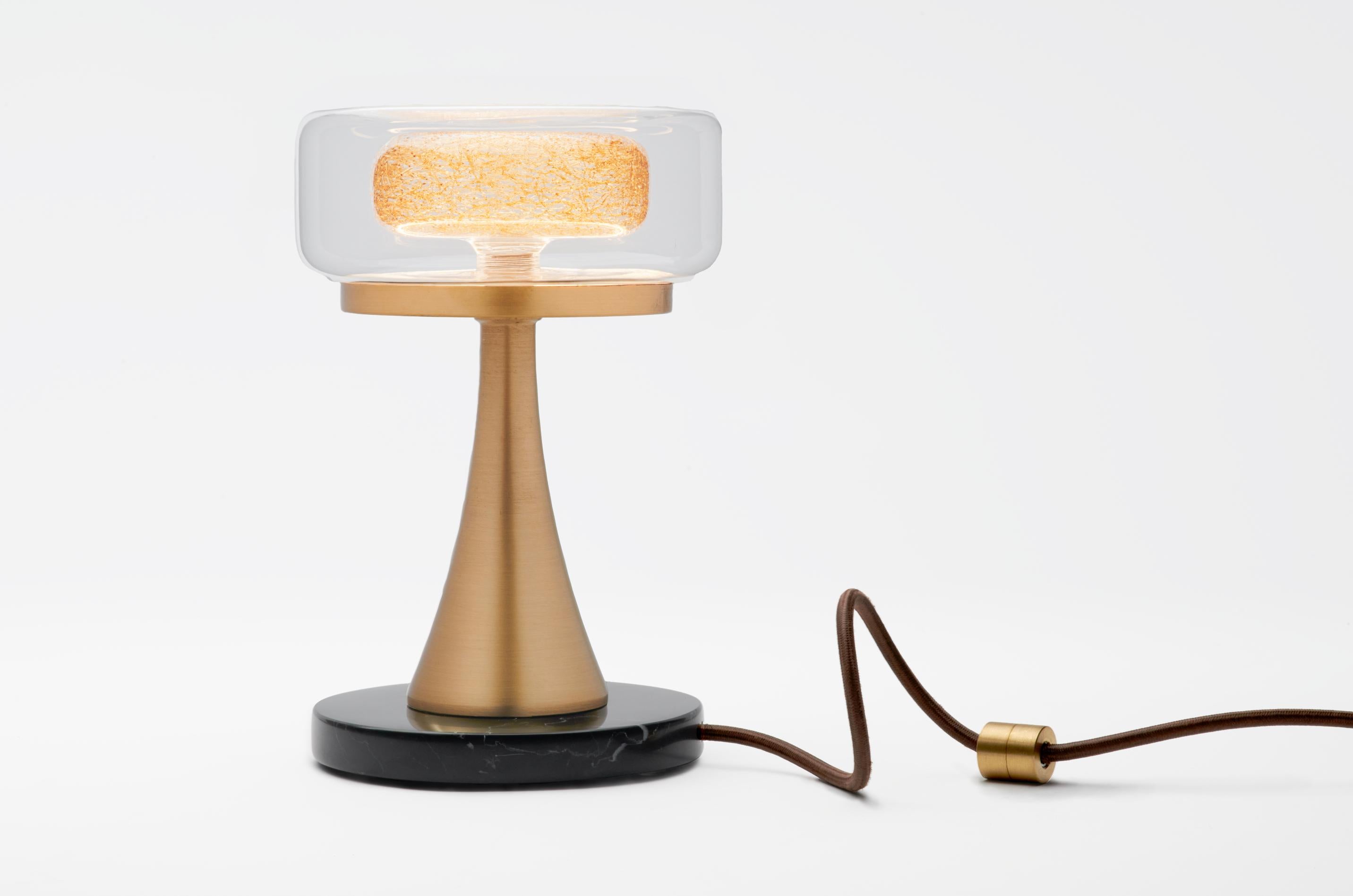 The Halo table lamp's ingenious design consists of glass, metal, and marble parts. The double glass pendant (our Halo design) rests on a metal plate, which is in turn balanced on cone shaped metal attached to a round marble base. The lamp is