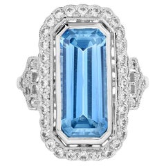 Bague Halona en or blanc 18 carats avec topaze bleue taille émeraude et halo de diamants