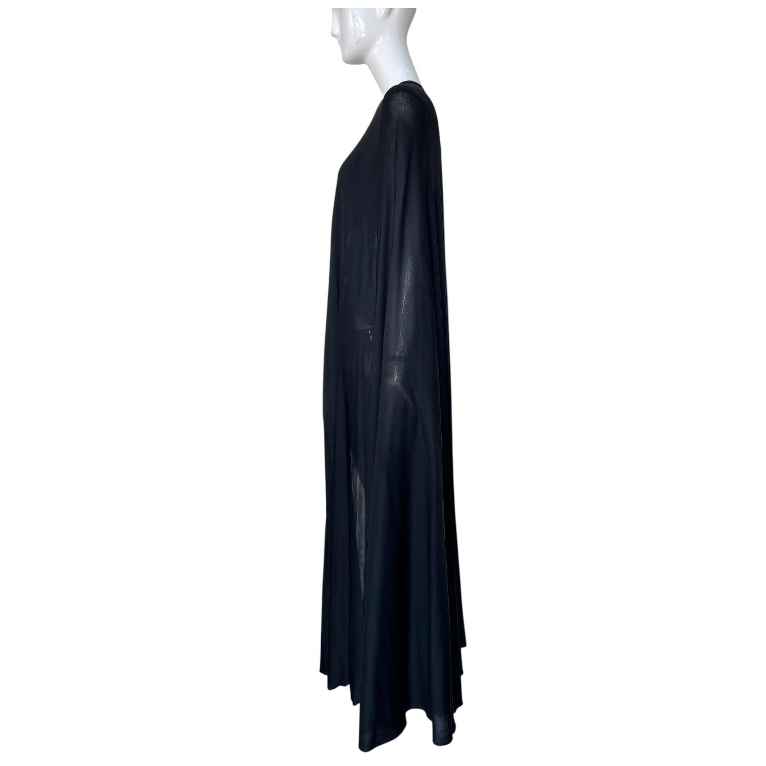 Meravigliosa e rara mantella di Halston risalente alla fine degli anni '70. Maglia in materia nera doppiamente foderata con chiusura a gancio singolo sul collo. Lunghezza al pavimento per una maggiore drammaticità. La mantella viene drappeggiata