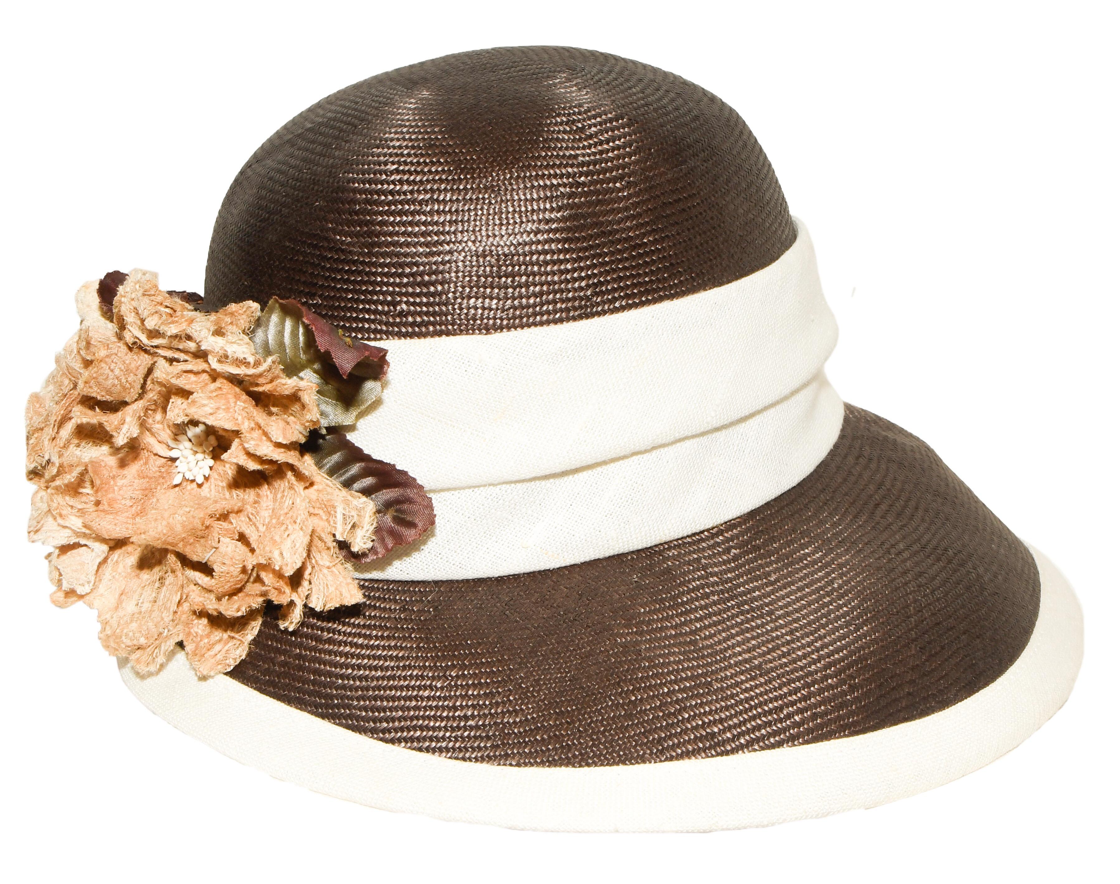 Halston beige and brown woven straw hat with beige linen band contains an upside down gondolier brim.  This stylish hat is lined with black grosgrain ribbon at the brim.  At the back it is adorned with beige linen flowers, for a dramatic look.  Hat