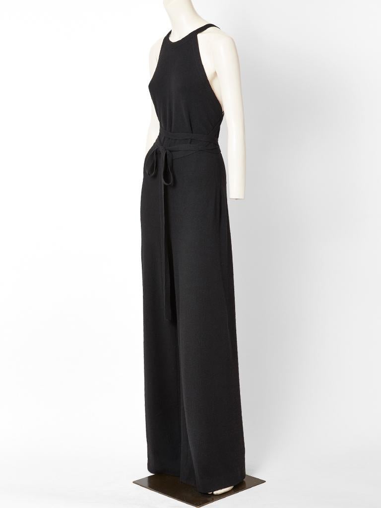 Halston, wool, cashmere knit, wide leg jumpsuit, having a halter cut neckline and a deep open back.
Jumpsuit has knit straps attached at the shoulders holding the piece up which criss cross at the back and continues to tie at the waist . C. 10970's.