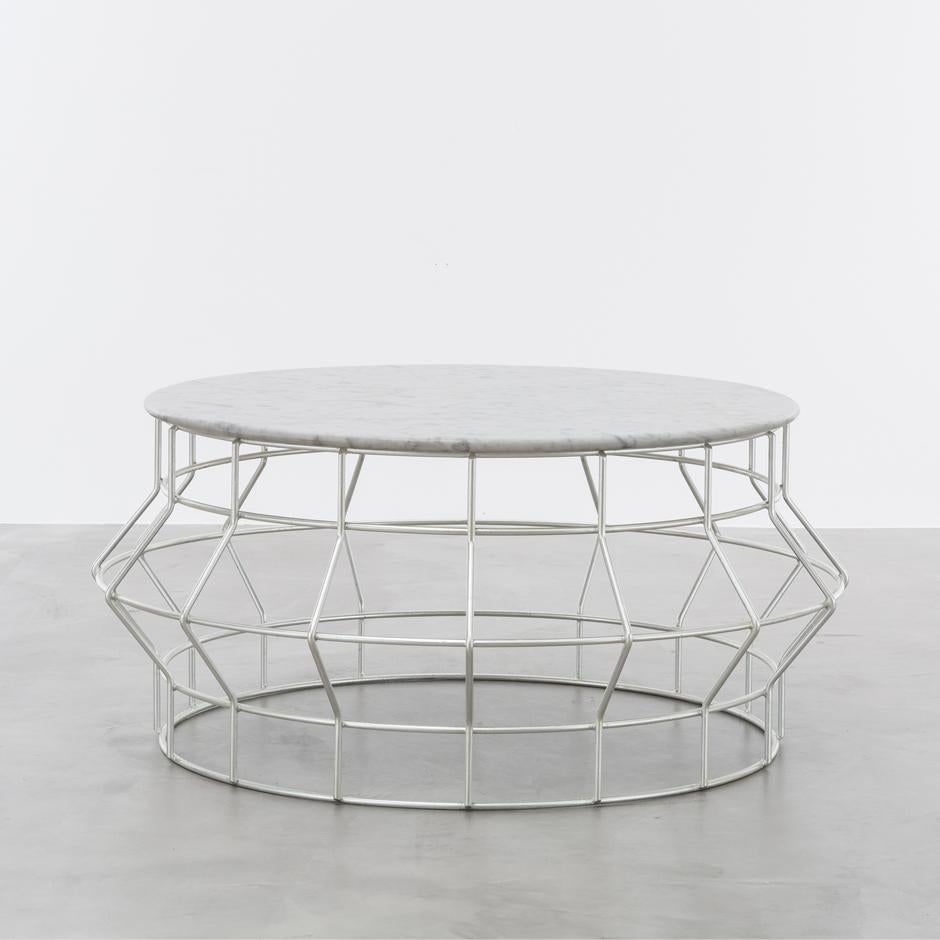 HALSTON COFFEE TABLE - Silver Leaf and Carrara Marble Top

The Halston coffee table is a modern and luxurious piece of furniture that combines style and function in a unique and beautiful way. This cocktail table is made of silver leaf over iron,