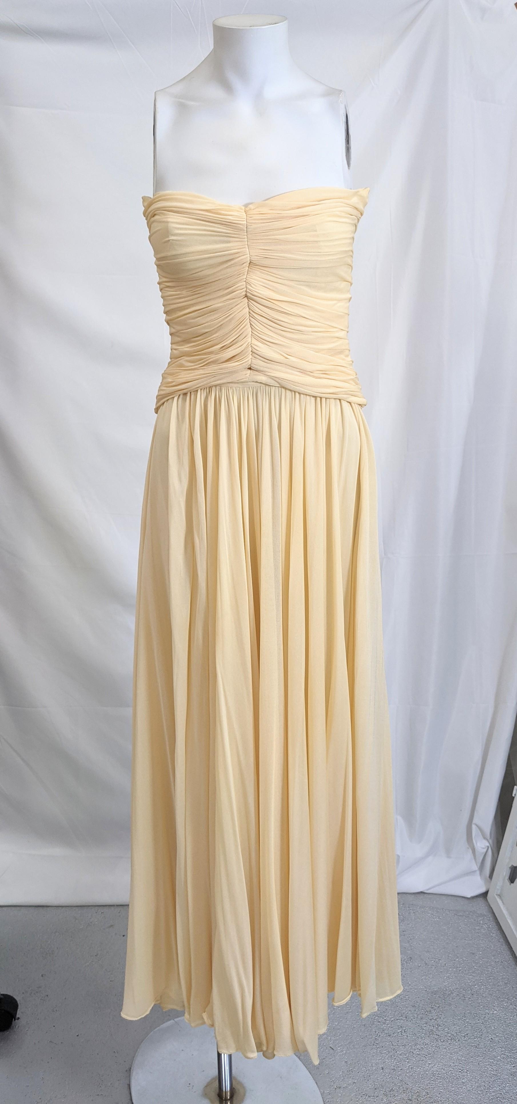 Halston's iconic ivory cream fine silk jersey two piece Grecian goddess dress. The separate strapless boned bustier bodice of ruched and pleated chiffon jersey. The long skirt loosely pleated with gathered waist. Very Good Condition. 
Length of