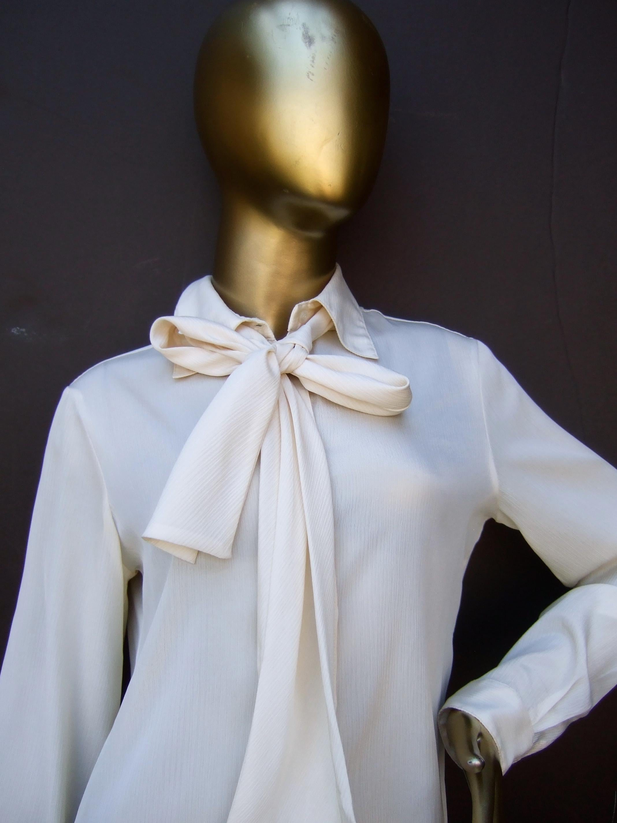 Halston VI Cream sheer polyester pussy cat bow blouse for Neiman Marcus c 1970s
The vintage designer blouse has a cream satin acetate collar & cuffs
The blouse & matching bow tie collar are constructed with a sheer light weight polyester fabric

The
