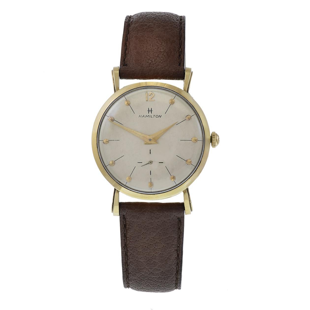 Introducing the timeless elegance of the Hamilton 1950s 14kt Gold 33mm Round Case with Extended Lugs Watch. This vintage masterpiece exudes sophistication with its classic round case crafted from luxurious 14kt gold, featuring extended lugs that add