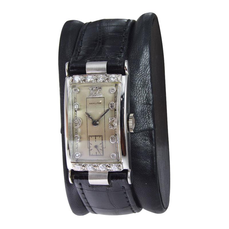 FACTORY / HOUSE: Hamilton Watch Company
STYLE / REFERENCE: Art Deco Gabled Crystal Diamond Bezel
METAL / MATERIAL: Platinum
CIRCA: 1940's
DIMENSIONS: Length 40mm  X Width 21mm
MOVEMENT / CALIBER: 17 Jewels / Tonneau Shape
DIAL / HANDS: Original /