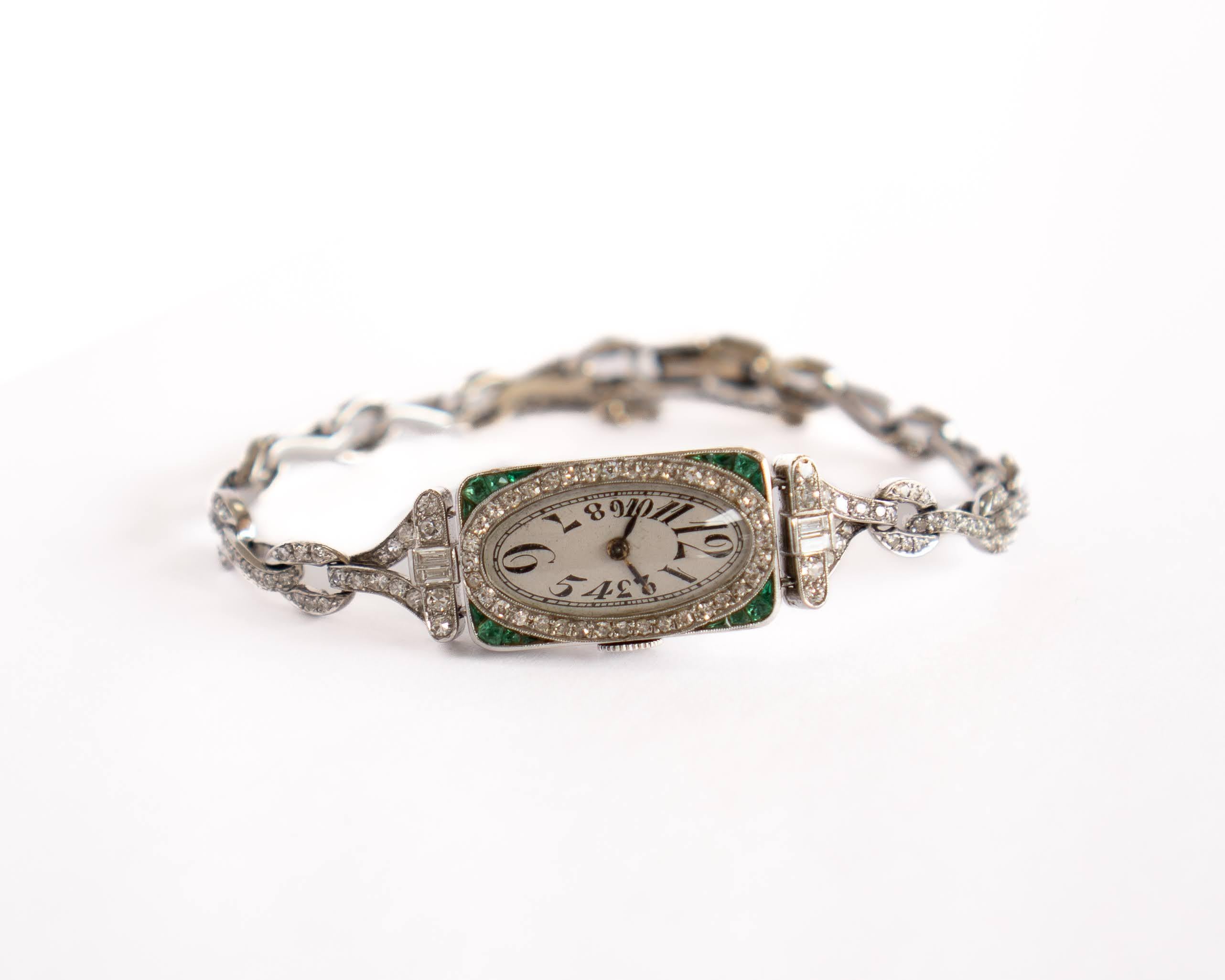 This Haas Neveux Lady's platinum vintage watch has a 14k white gold link-style bracelet with a white gold diamond case frame and natural emerald gemstone corners. This piece features 197 round bezel settings, 4 rectangular channel settings and 16