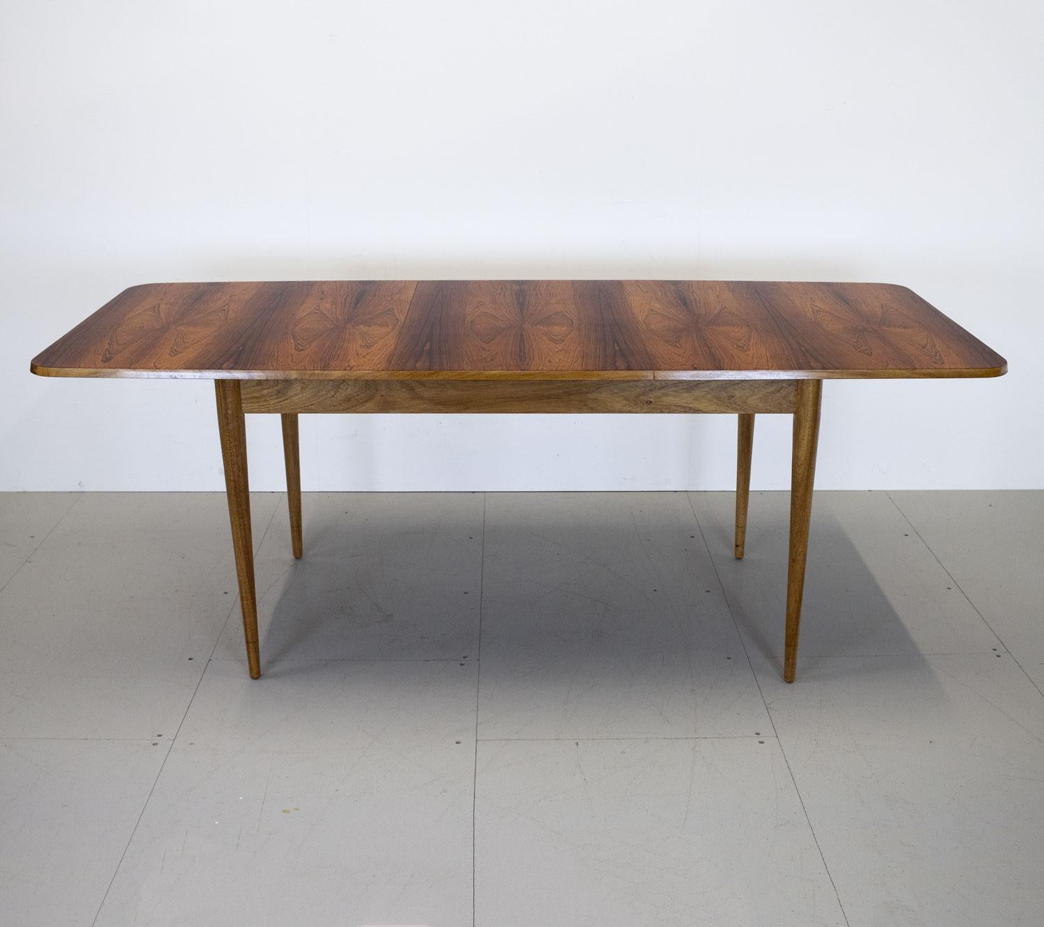 1960s Hamilton rosewood extending dining table by Robert Heritage for Archie Shine. This table which has a beautiful rosewood grain wits on an oak frame with tapering legs. It has one extra leaf which can be stored under the table and can seat 6-8