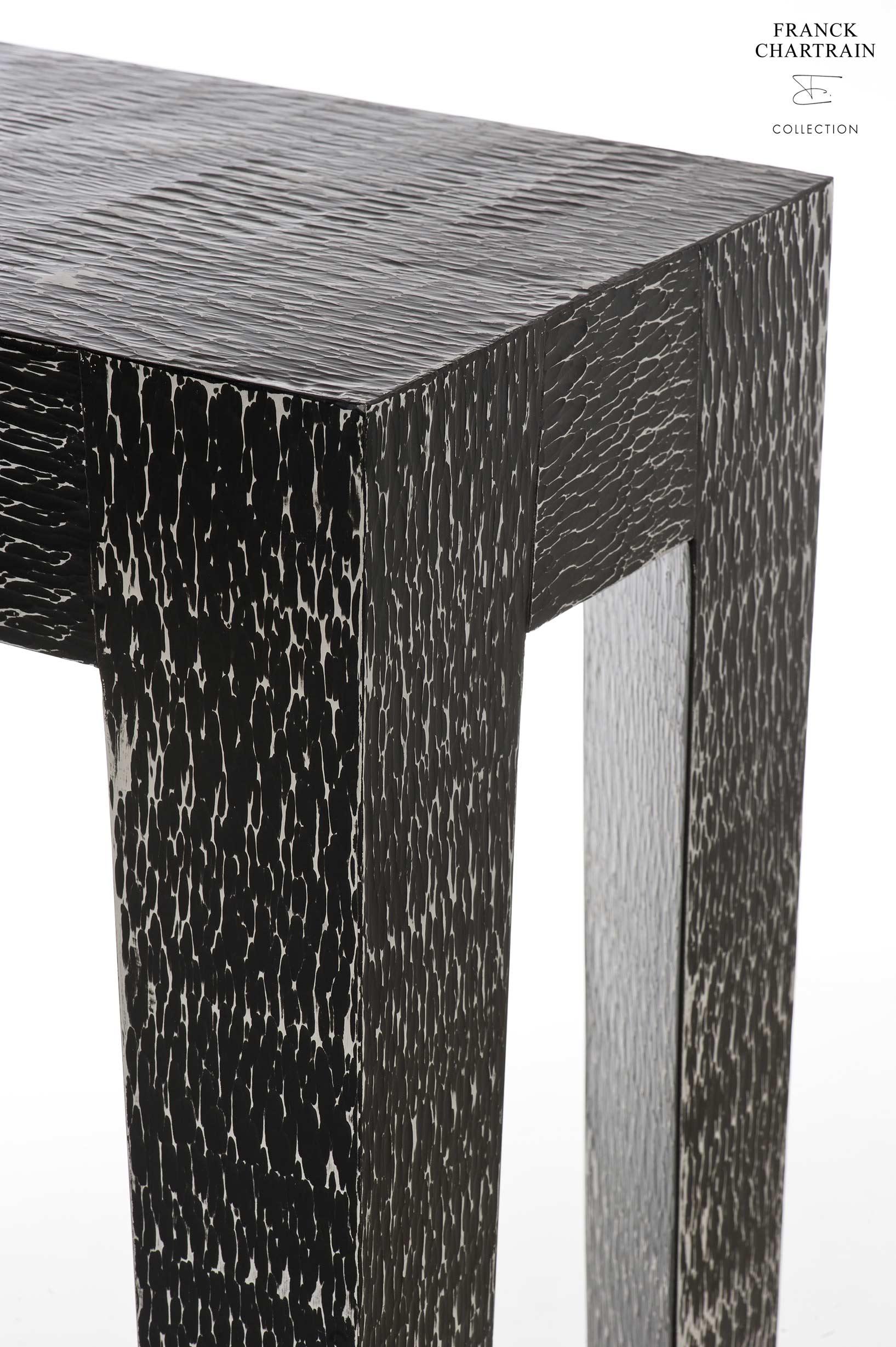 This console, with African inspiration, made by famous French artist-designer.

This hammered console is in aluminum, it is showing an ethnic texture with a black matte finish.
The massive tapered legs describe a prism shape.
As the structure allows