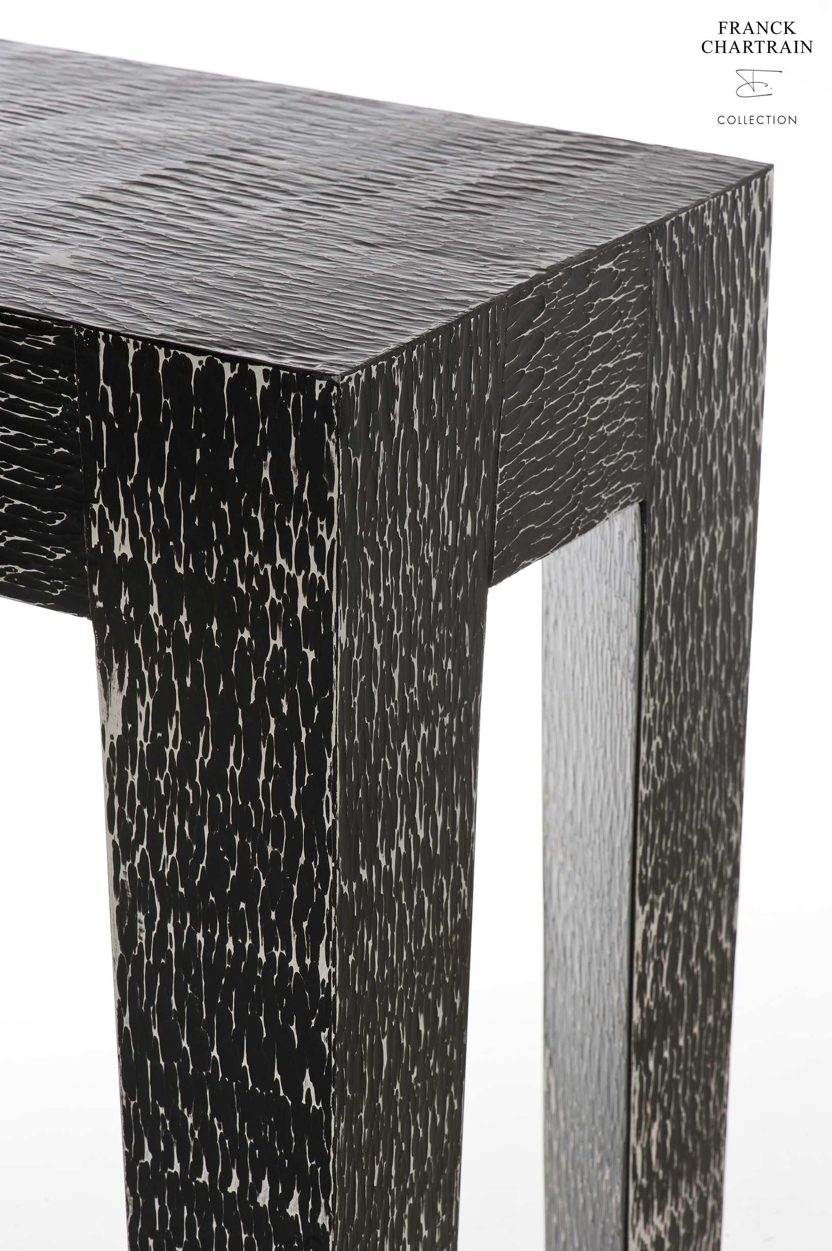 This console, with an African inspiration, is hanmade by the famous French artist-designer Franck Chartrain

This hammered console is in aluminum; it is showing an ethnic texture with a black matte finish.
The massive tapered legs describe a prism